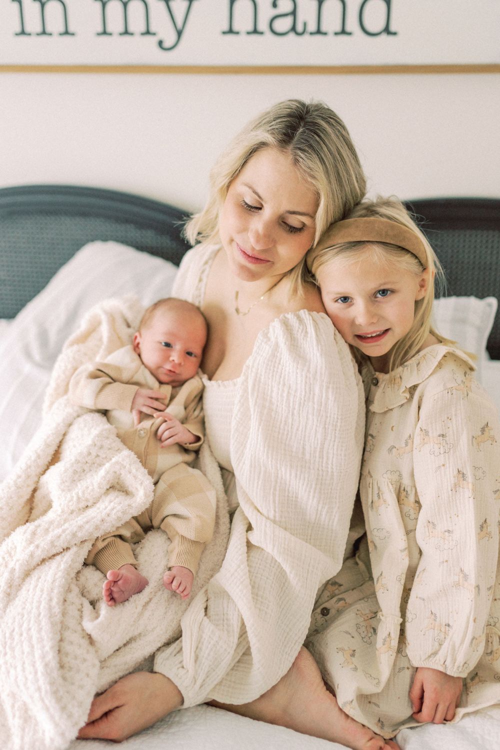 A tender family moment on a bed showing affection between parent and children in soft white clothing.