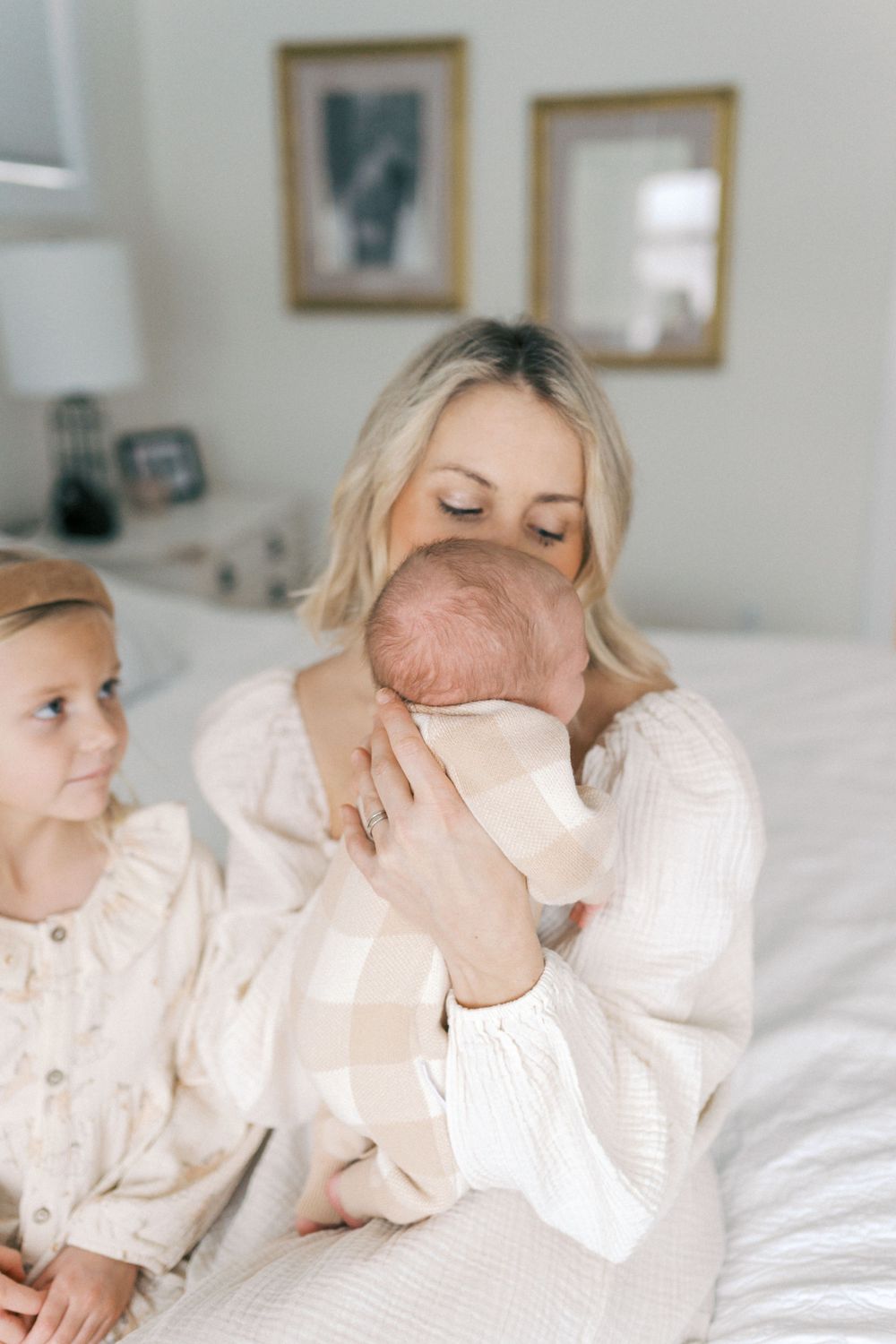 Family cuddle moment on bed with everyone dressed in soft white clothing.