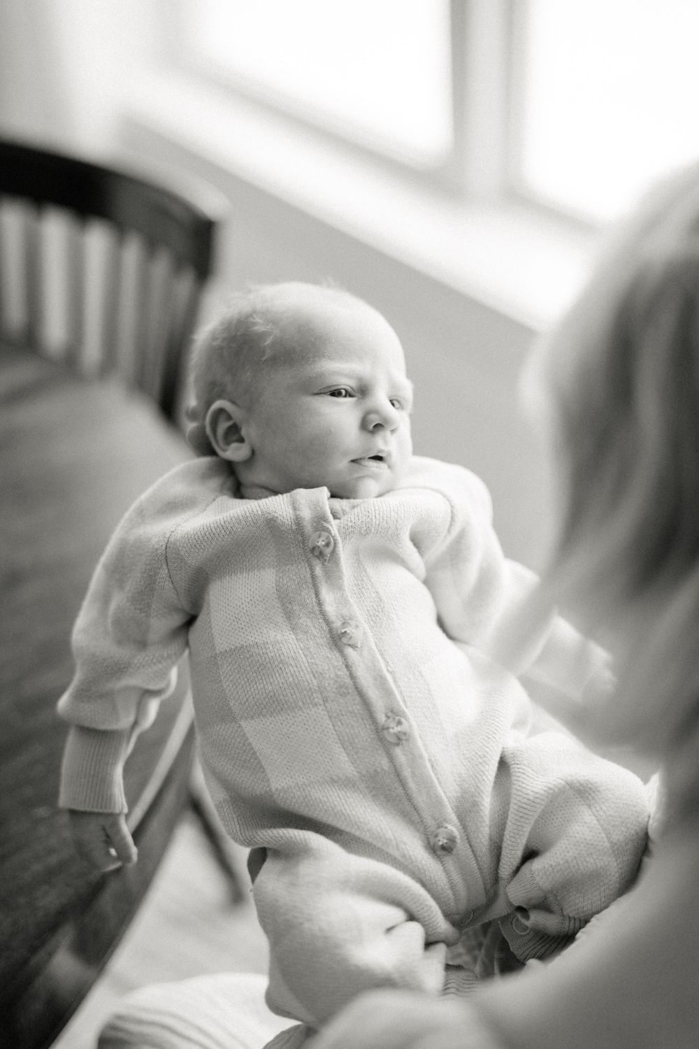 Black and white portrait of baby in buttoned sleepwear.