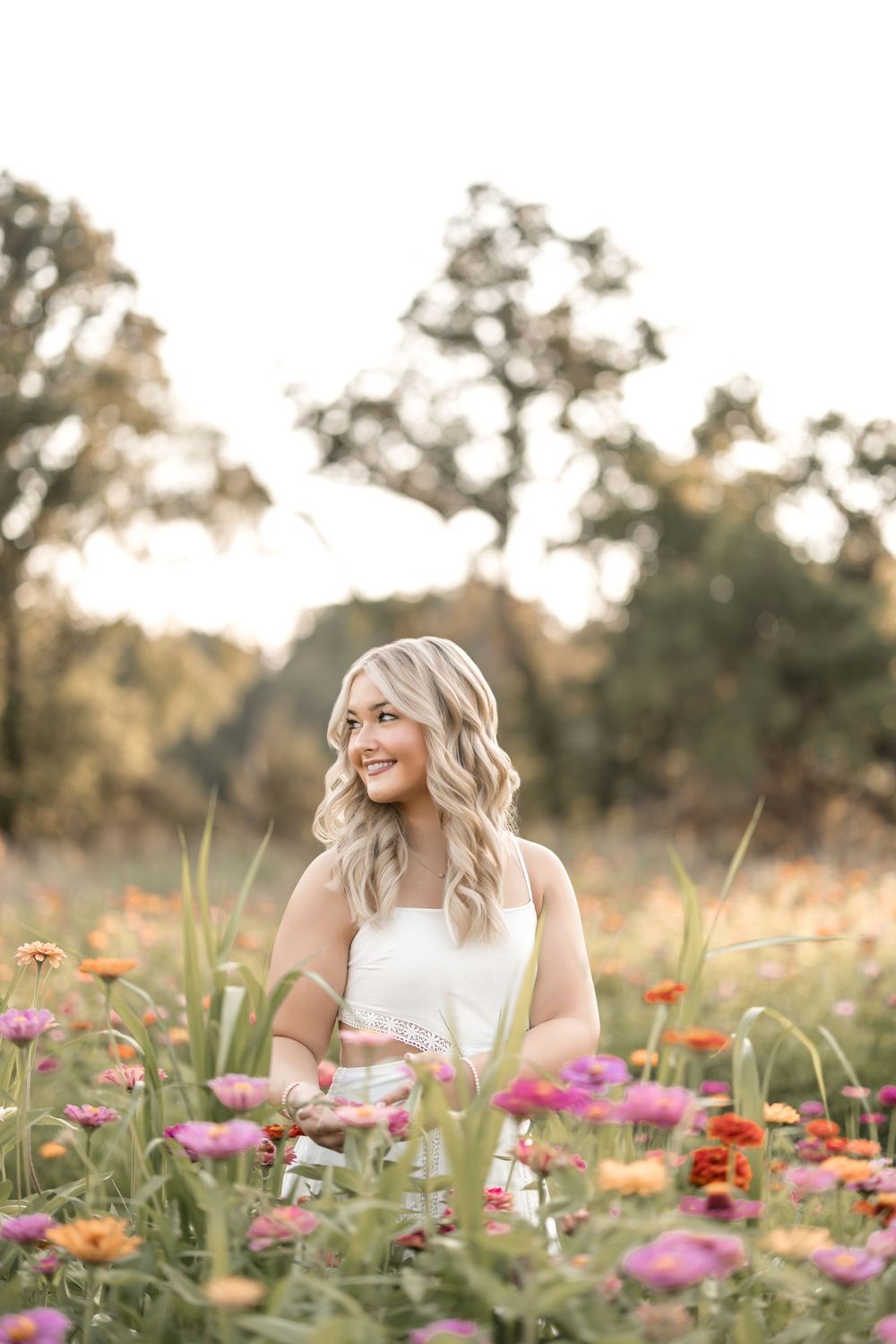 A joyful portrait in a wildflower field with colorful zinnias and cosmos flowers at golden hour.