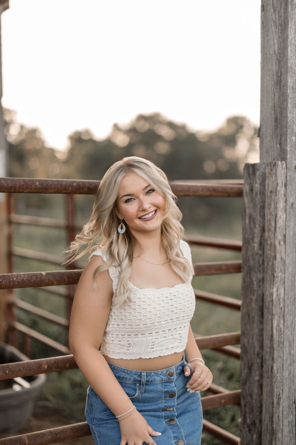 A casual summer portrait by a rustic wooden fence during sunset.