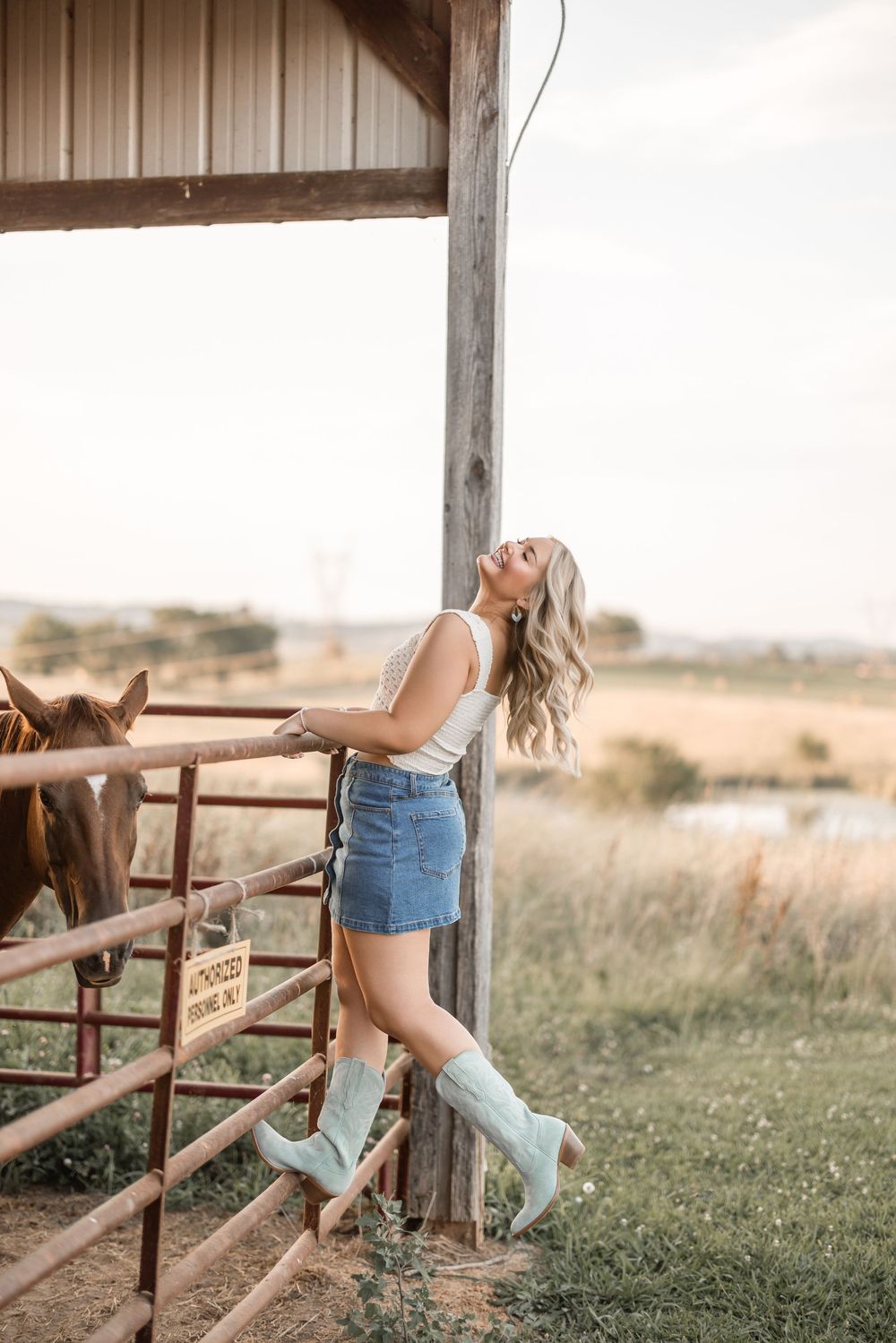 A dreamy rural portrait showcases turquoise cowboy boots and a denim skirt against a rustic barn setting.