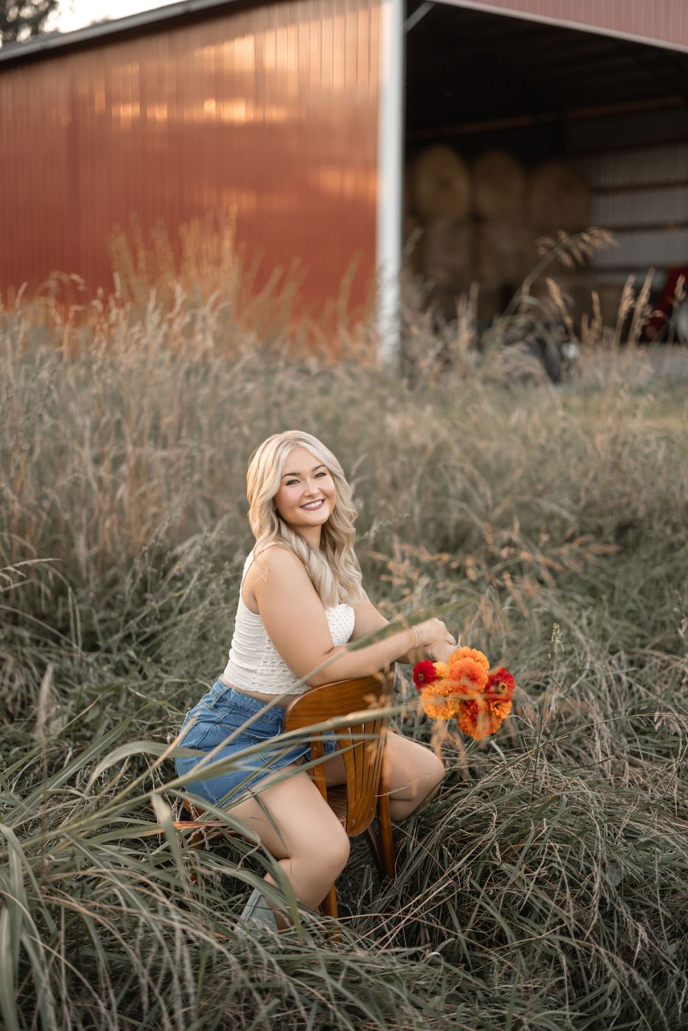 A carefree summer portrait with orange flowers near a rustic red barn.