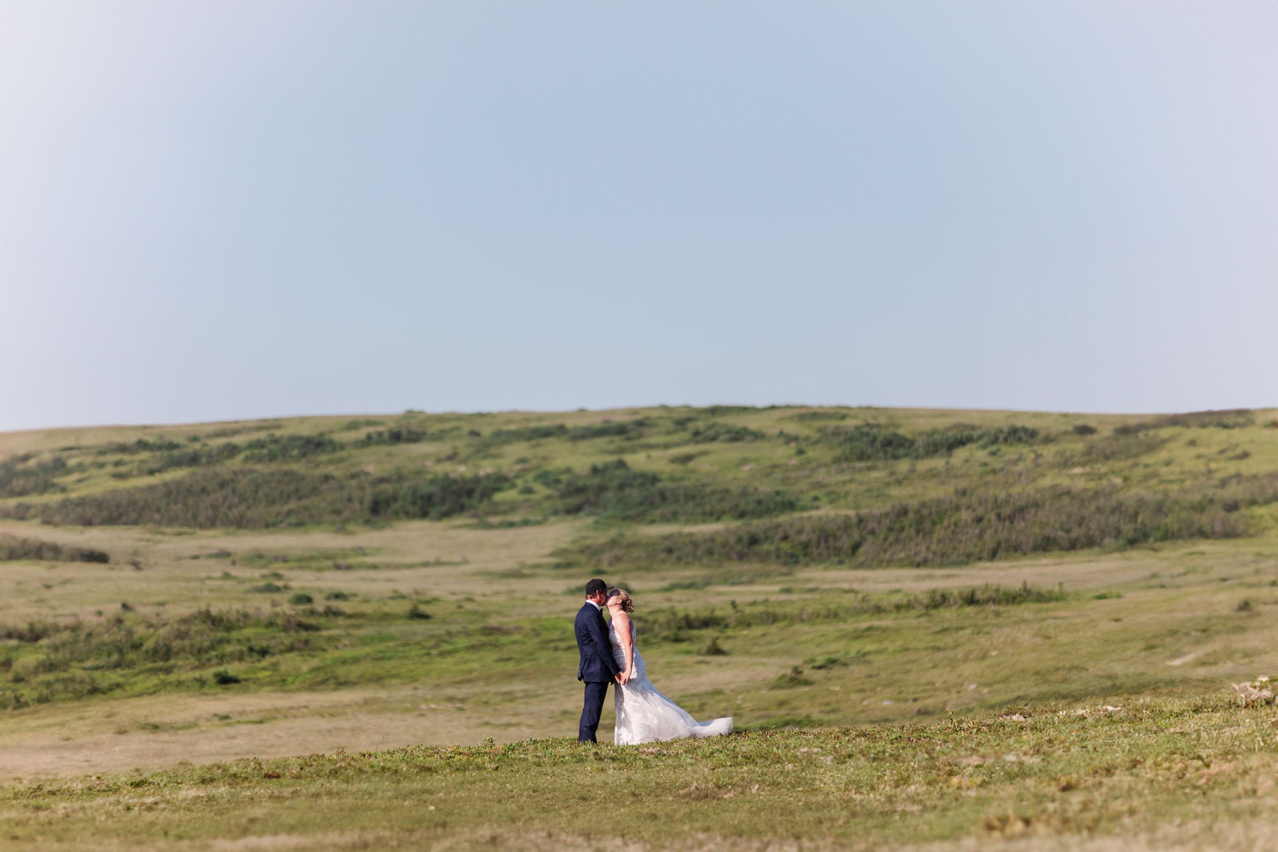 A sequence of rolling green hills and moorland landscapes stretches across the horizon under cloudy skies.