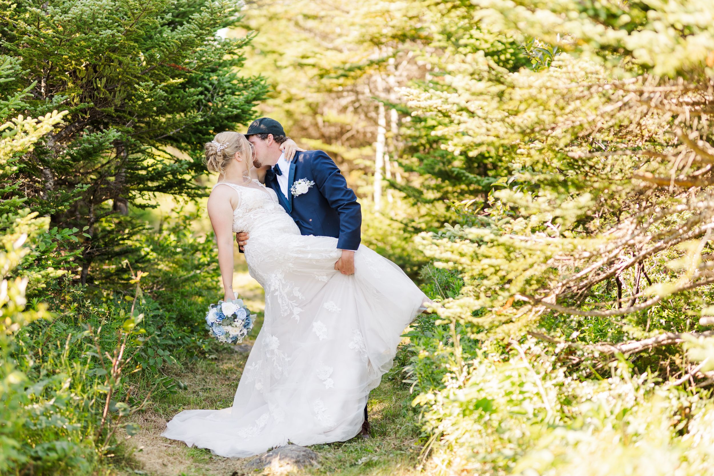 Romantic moments captured between a couple in white wedding attire surrounded by lush forest greenery and sunlight.