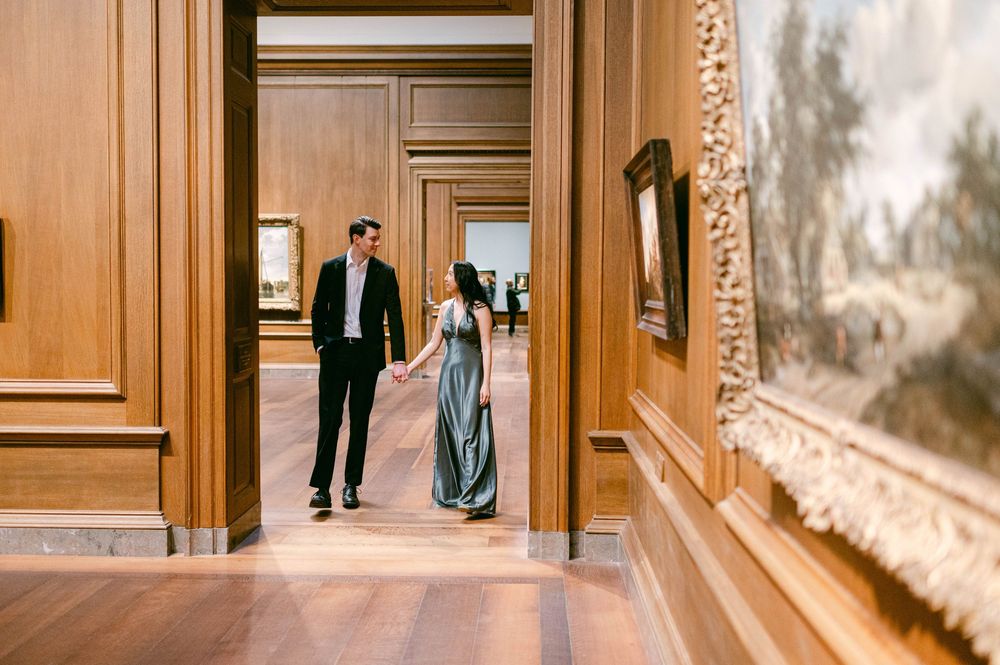 Elegant couple photographed walking through grand wooden hallway.
