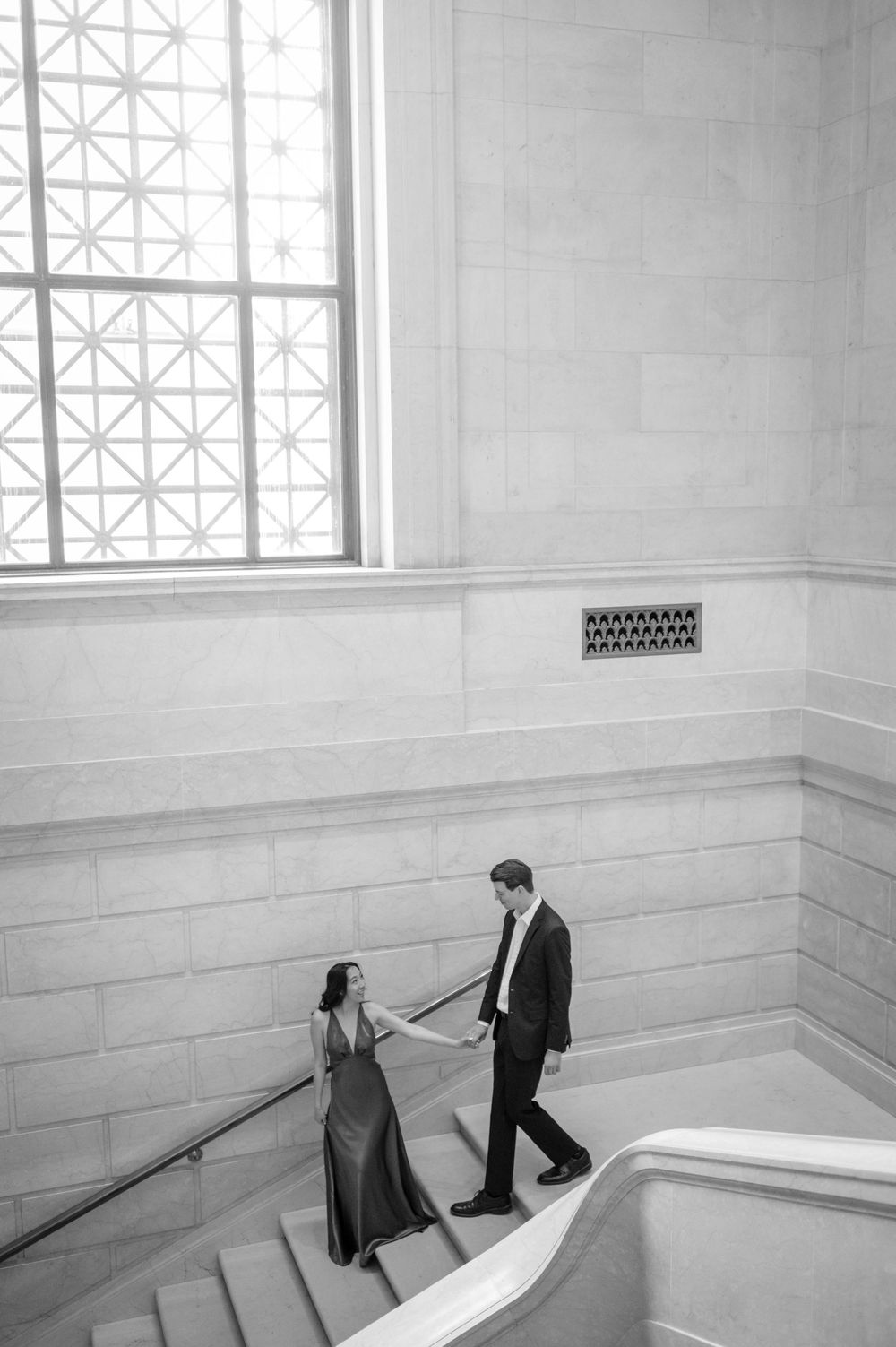 Black and white photo of couple dancing on elegant marble staircase.