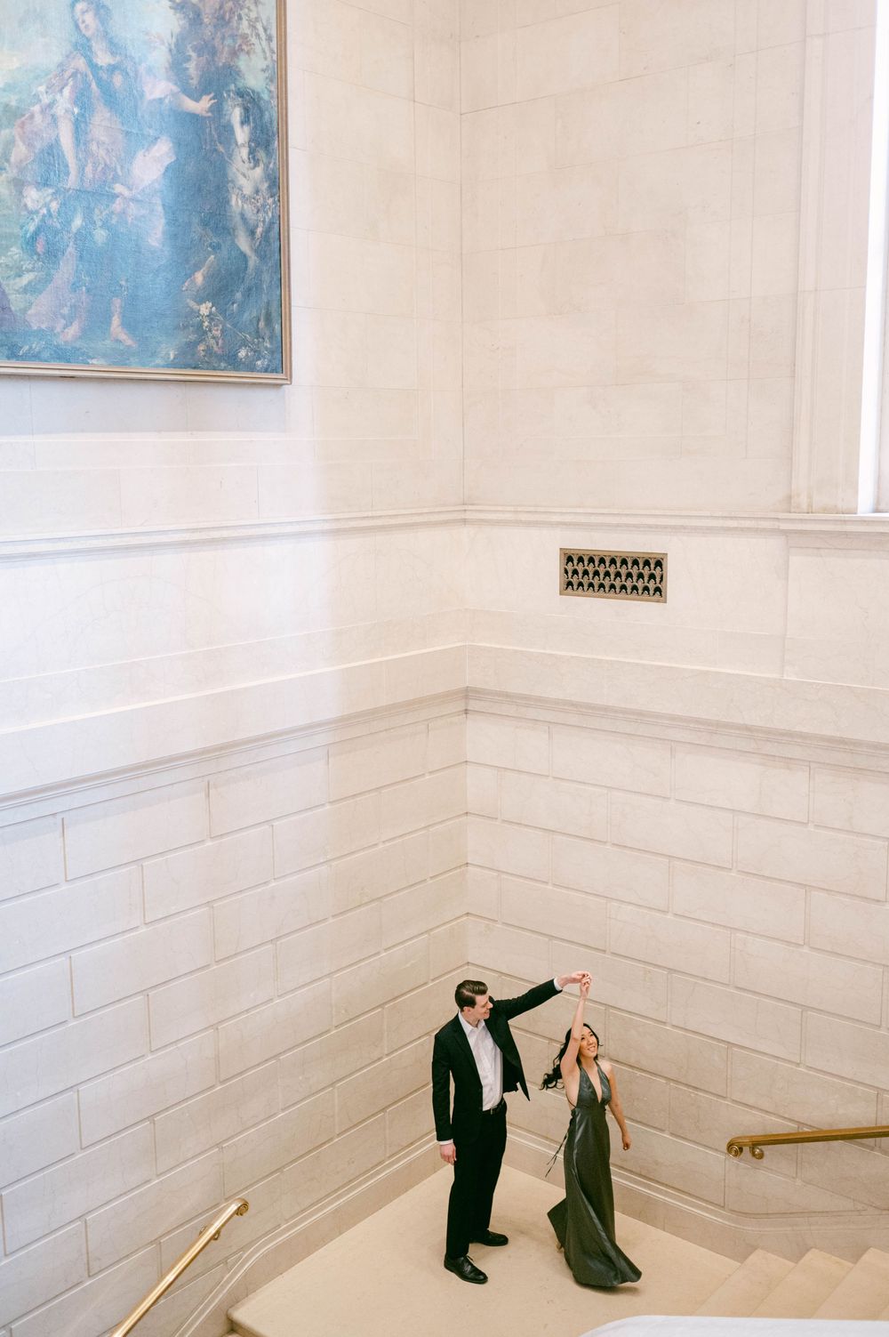 Couple performing dance moves in bright interior with artwork on wall.