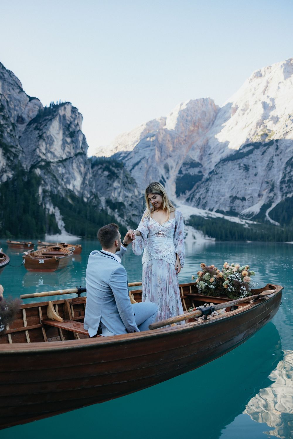 A couple shares an intimate moment on a wooden boat on the turquoise waters of Lake Braies in the Dolomites.