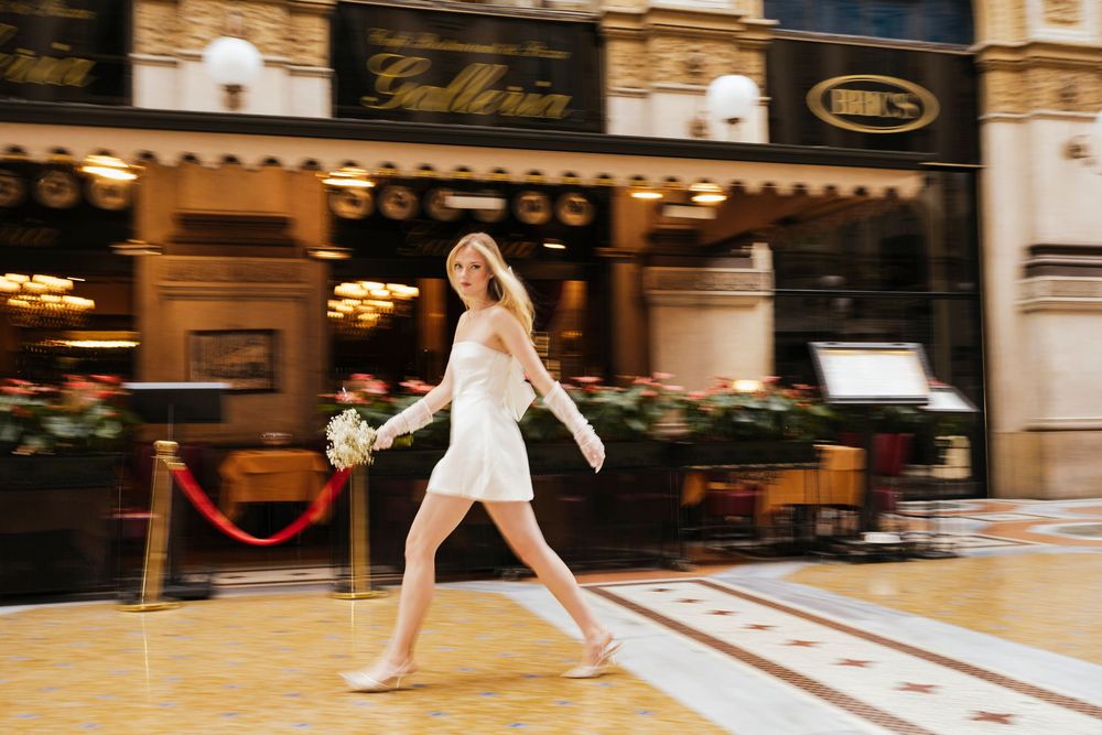 Figure skater in elegant white dress performs graceful spin on indoor ice rink under warm lighting.