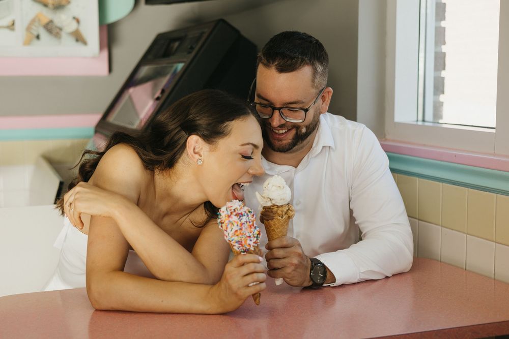 A couple shares ice cream cones and laughs together at a retro-style diner booth at Merla Mae in London. London Wedding photography