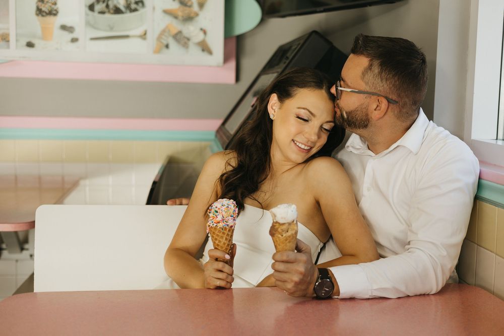 A romantic couple shares sweet moments while eating ice cream together on a comfortable couch.