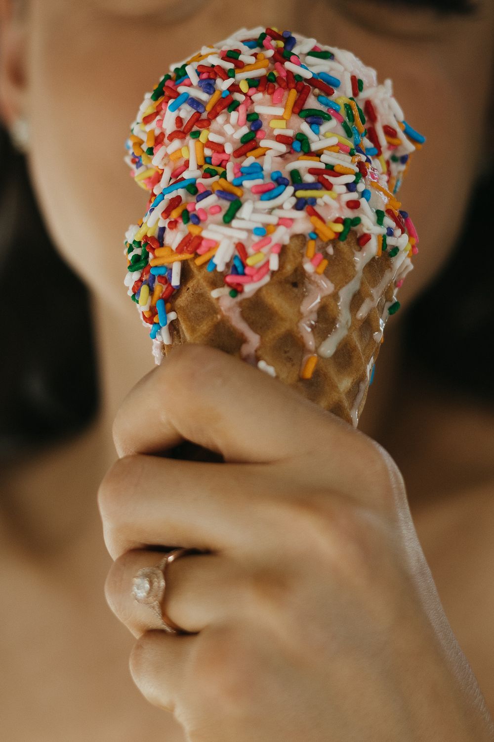 Close-up of a white chocolate-dipped ice cream cone topped with colorful rainbow sprinkles.