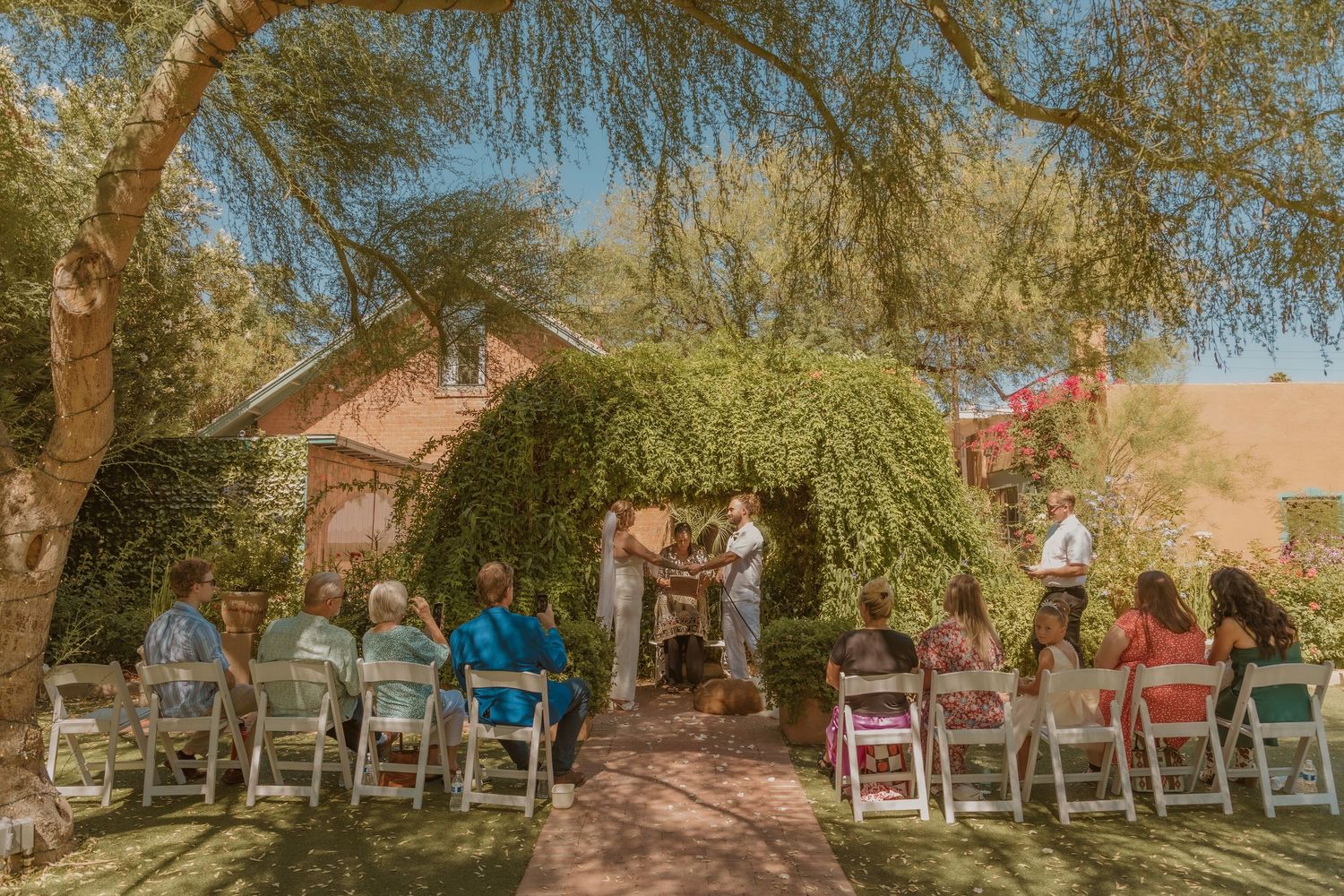 A romantic desert wedding ceremony on a sun-drenched balcony with a cactus silhouette at sunset.