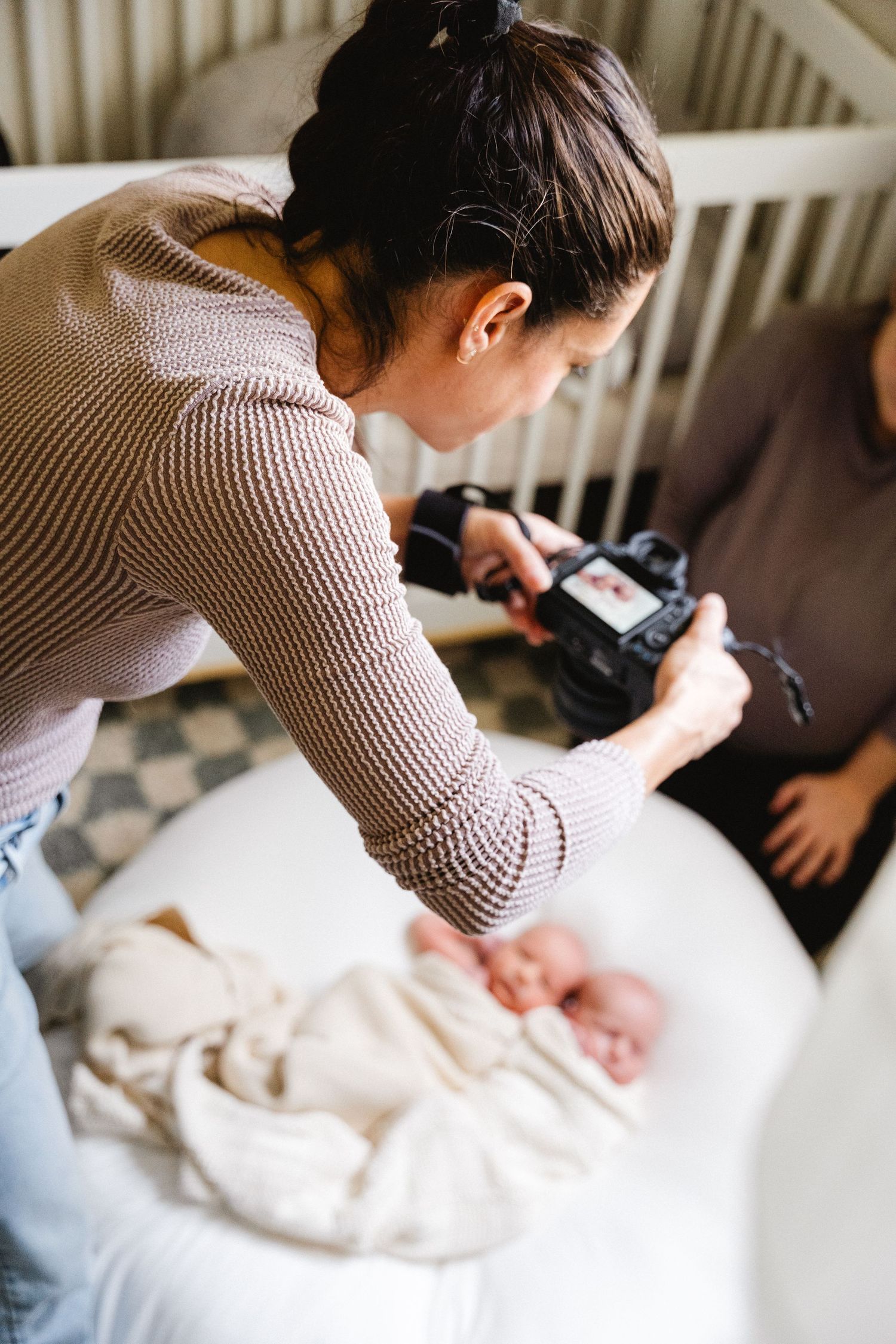Photographer in knit sweater taking lifestyle photos in bright interior space.