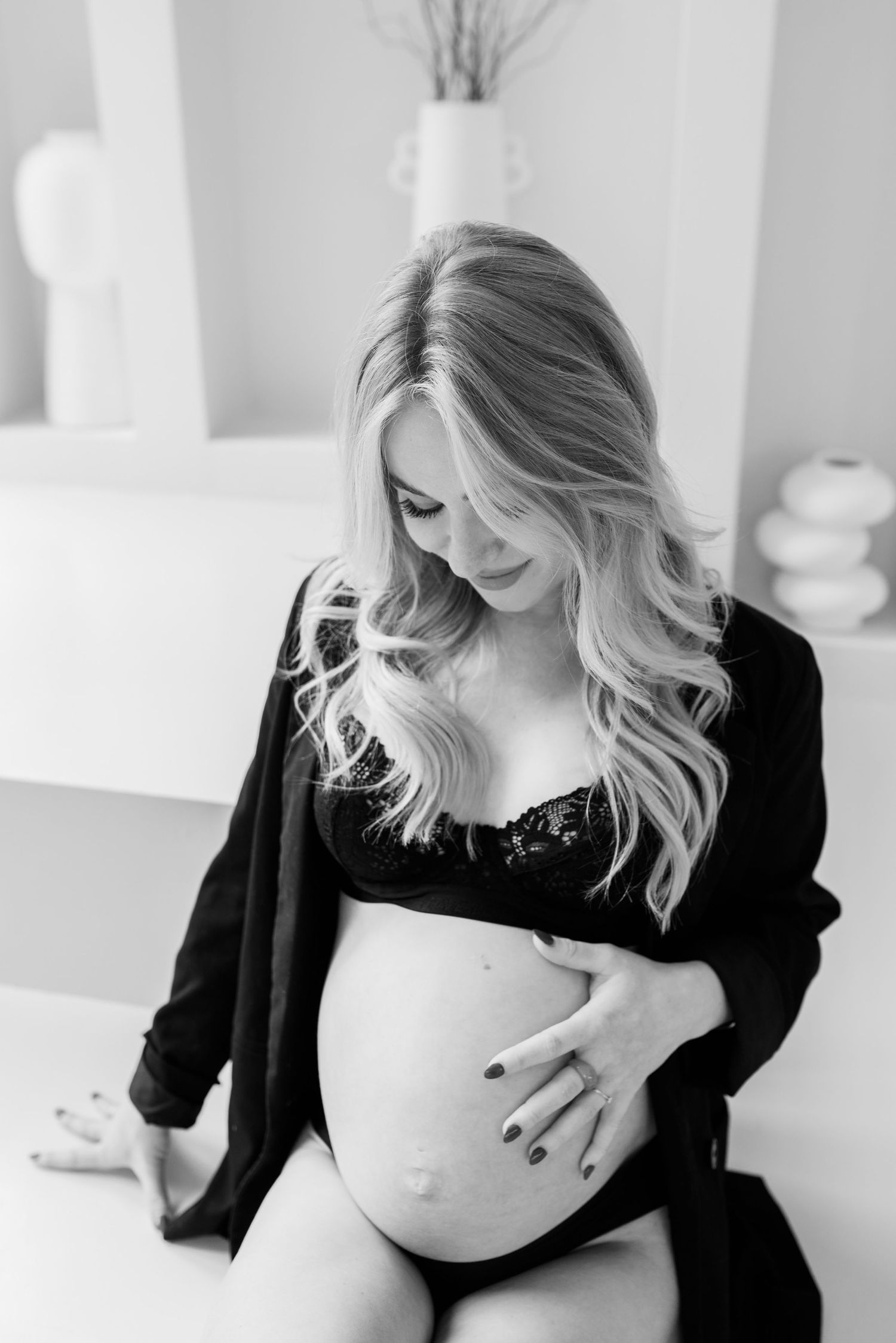 A series of black and white maternity photos showing a pregnant woman in a black top against a light background.