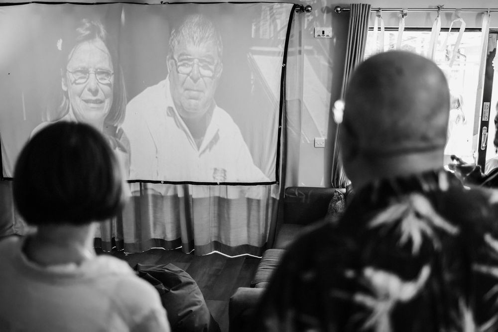 Black and white photo of people watching a projected film or video display in a darkened room.