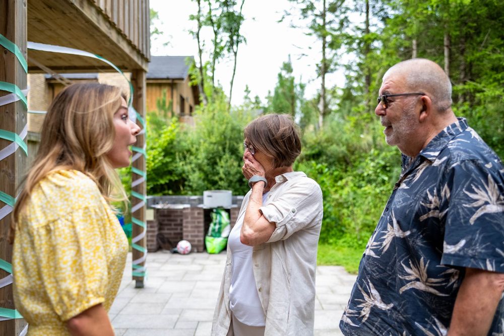 People enjoying a relaxed outdoor gathering on a porch with bright greenery in the background.