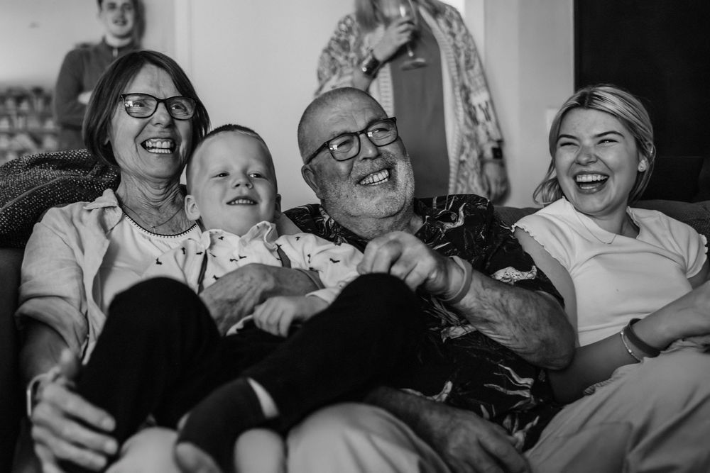 A collage of black and white photographs showing people laughing together in candid moments of joy and connection.
