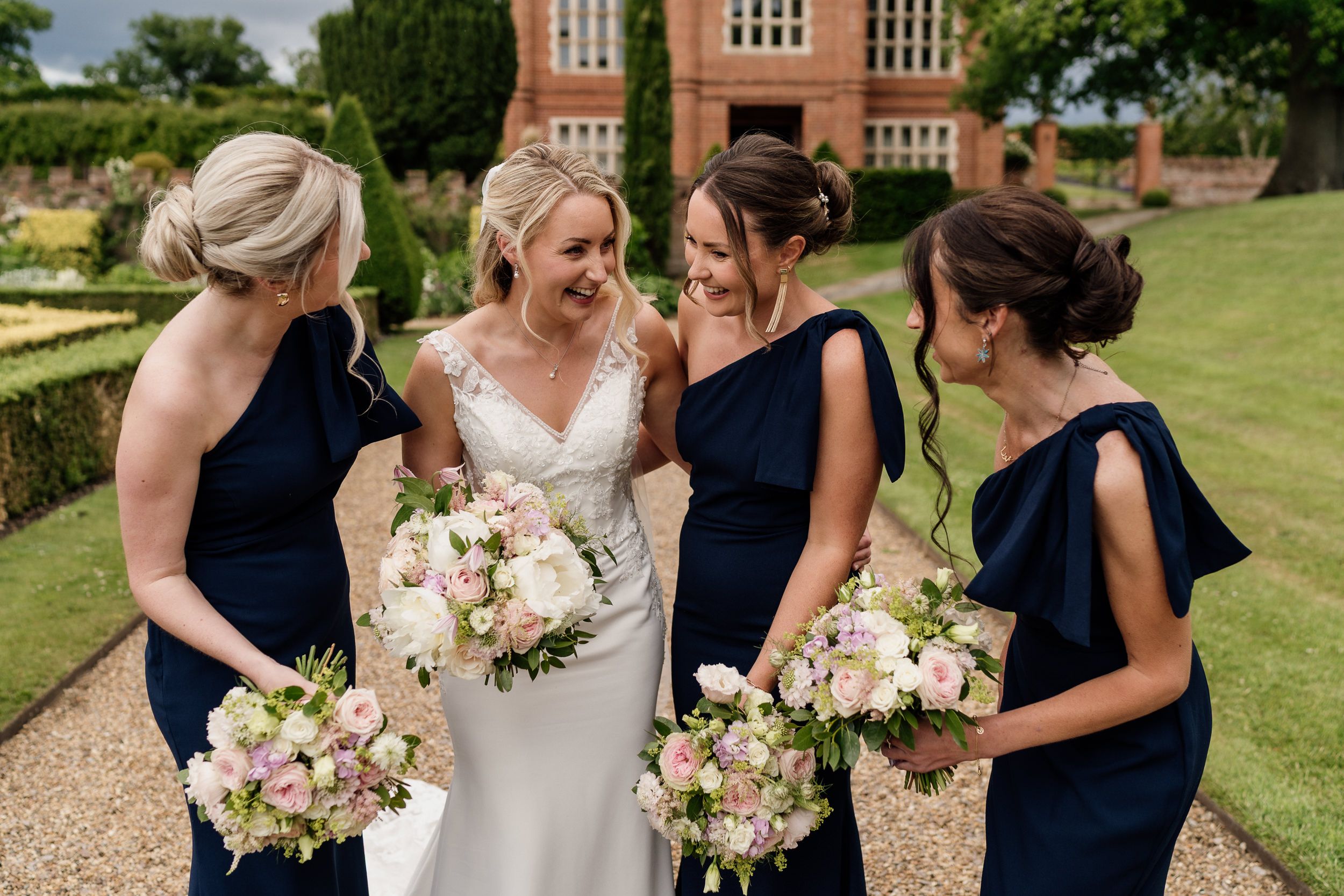 Bridesmaids in navy dresses sharing a joyful moment with the bride.