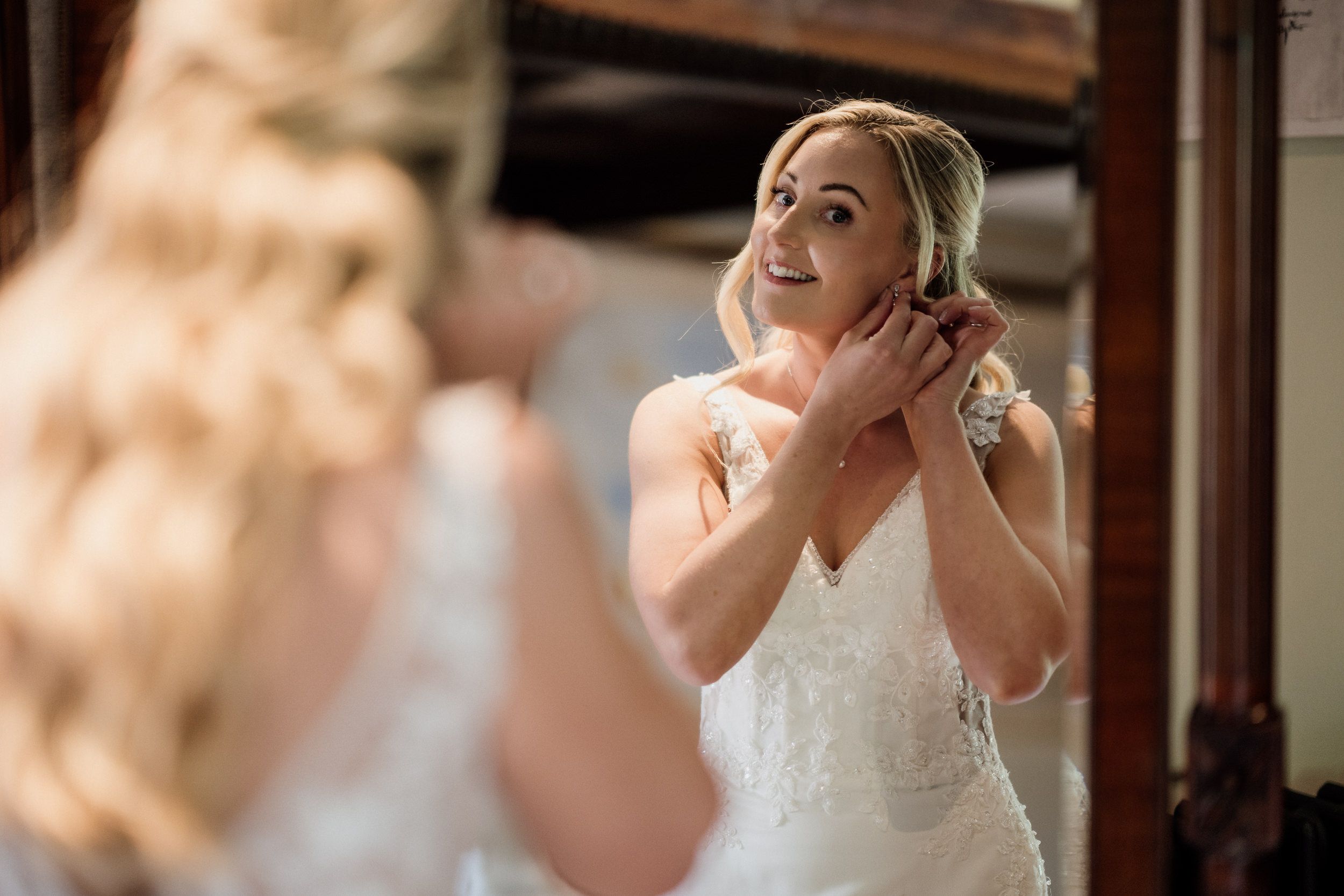 A bride wearing a classic white wedding dress reacts emotionally while reading a letter before her ceremony at Oxnead Hall in Norfolk.