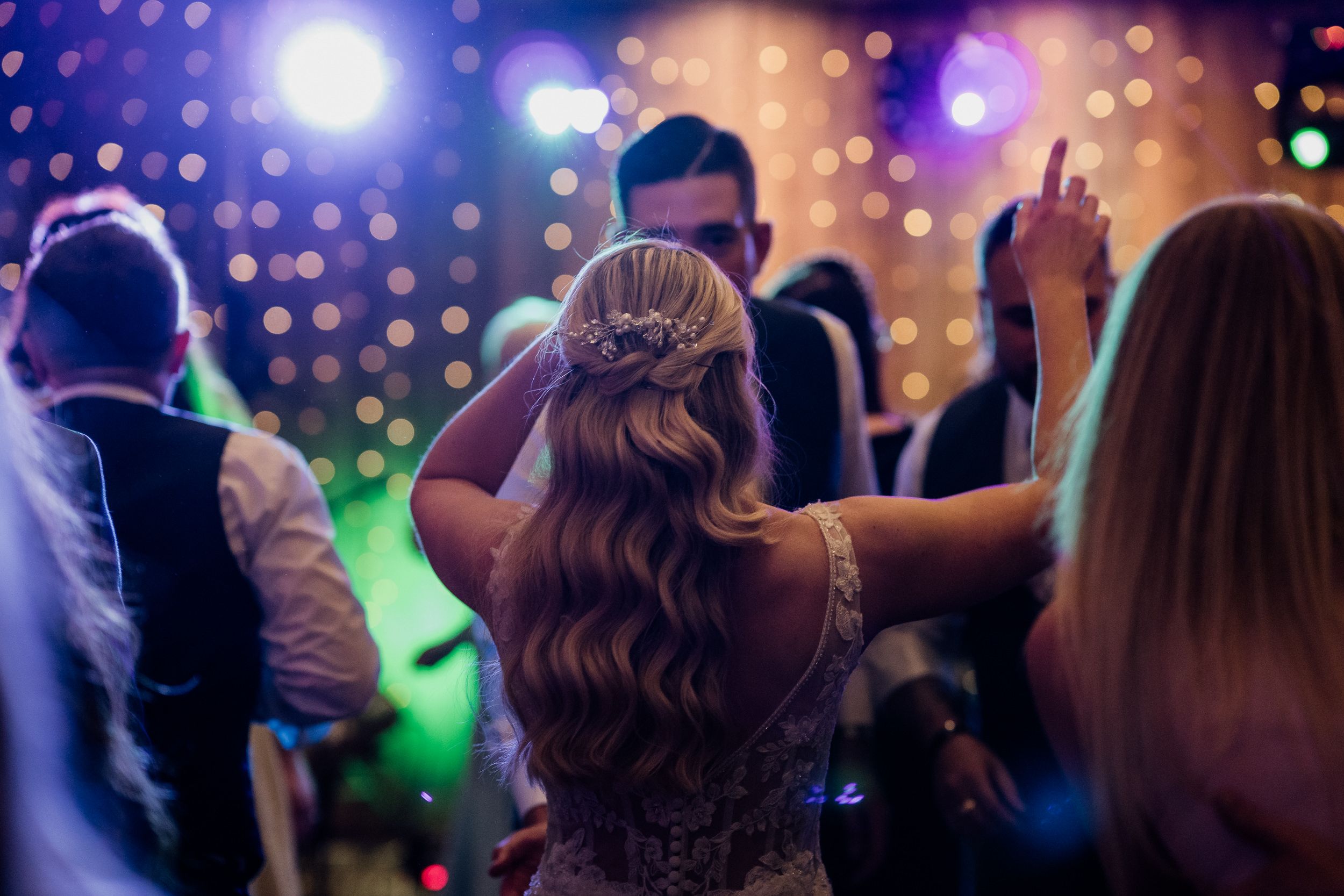 Blurred silhouettes of people partying and dancing at a nightclub with colorful lights and bokeh effects in the background.