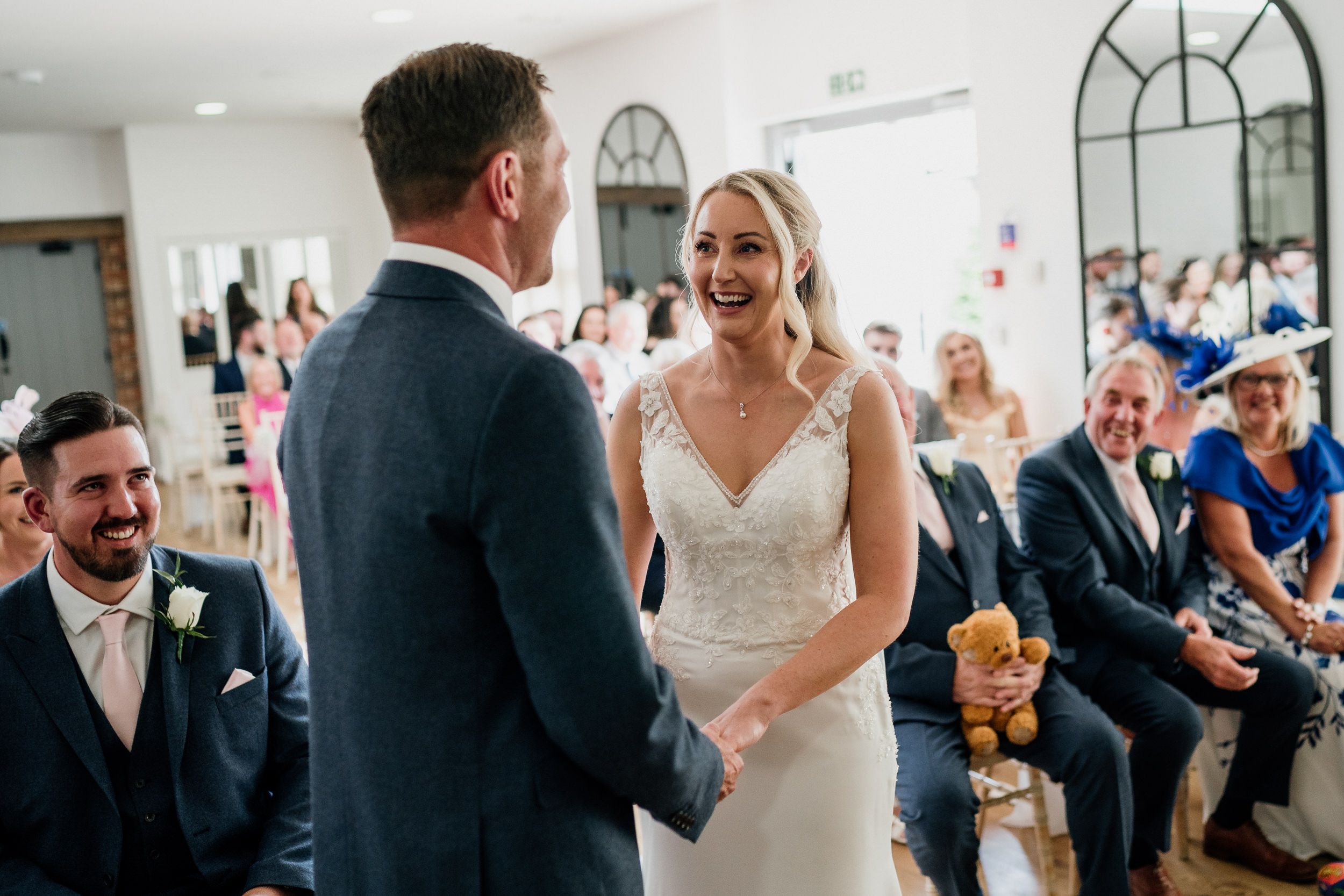 Joyful wedding ceremony at Oxnead moment with couple exchanging vows in bright indoor venue.