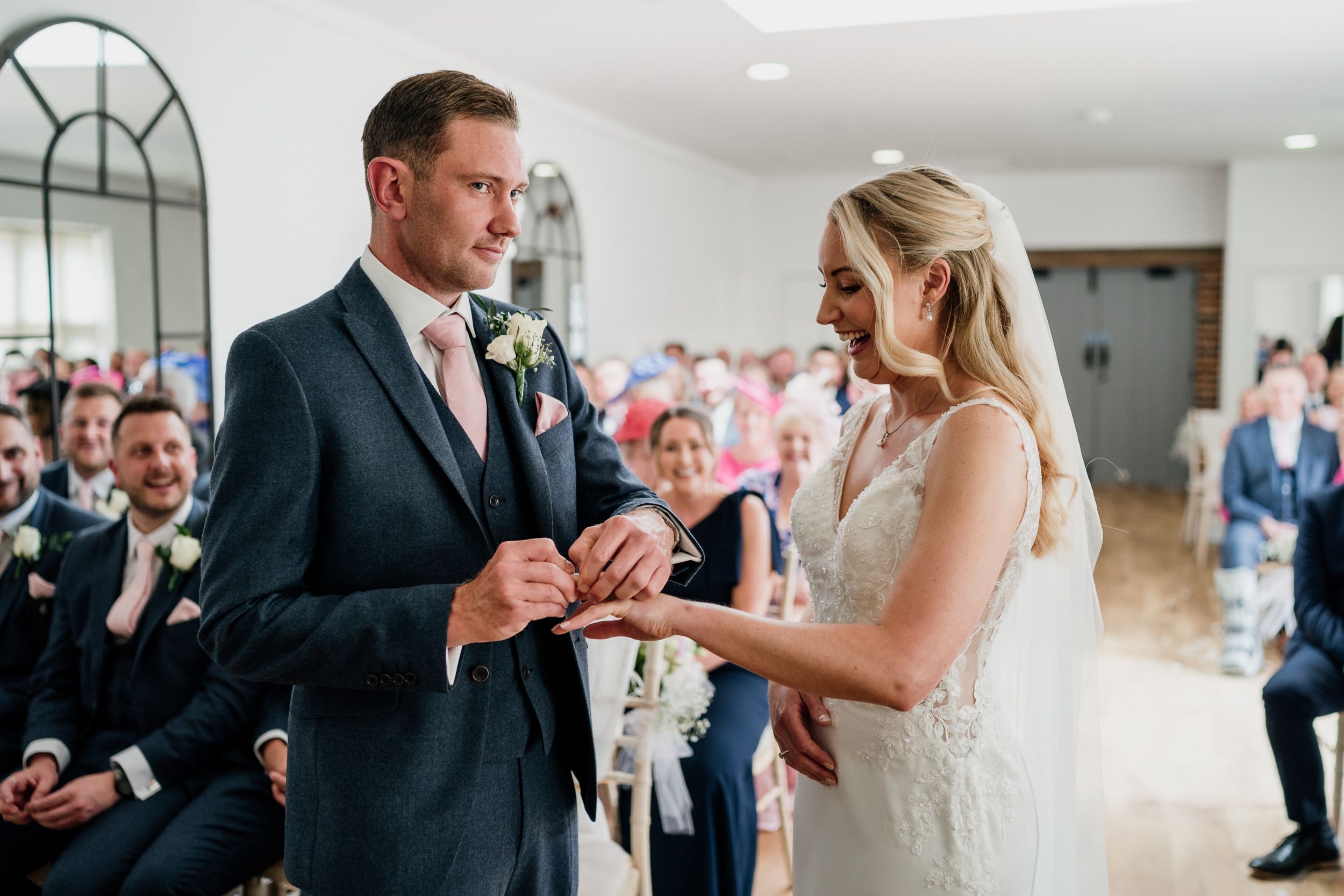 Couple exchanging rings during an intimate indoor wedding ceremony at Oxnead Hall.