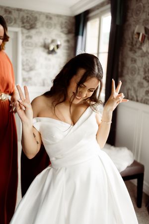 A figure in a white wedding dress twirls playfully while getting ready in an elegant room.