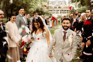 A joyful newlywed couple walks down an outdoor aisle while guests toss rose petals during a garden wedding celebration.