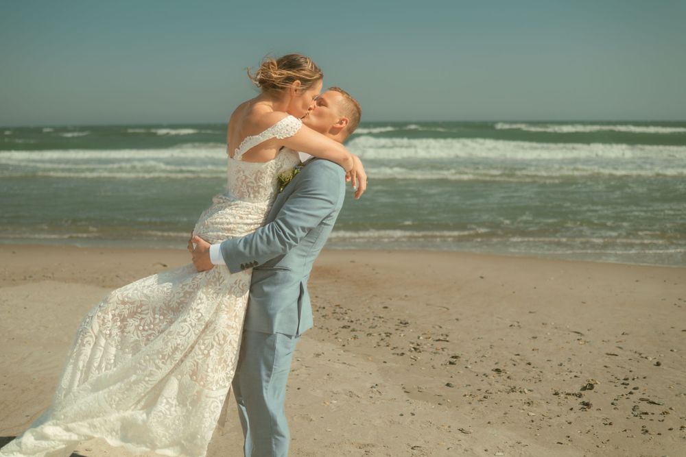 Romantic moment with couple embracing on beach in formal wedding attire.