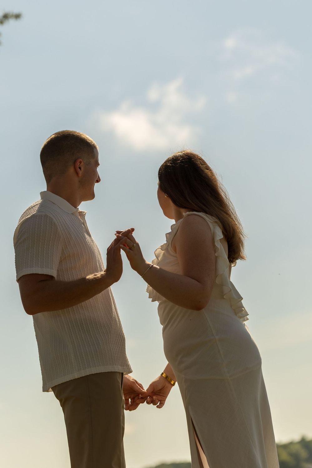 Couple in white clothing shares an emotional exchange during sunset.