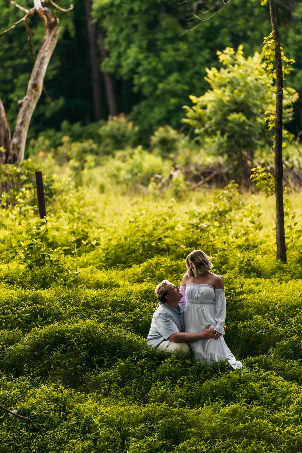 Couple relaxes in lush green ferns during intimate forest photoshoot.