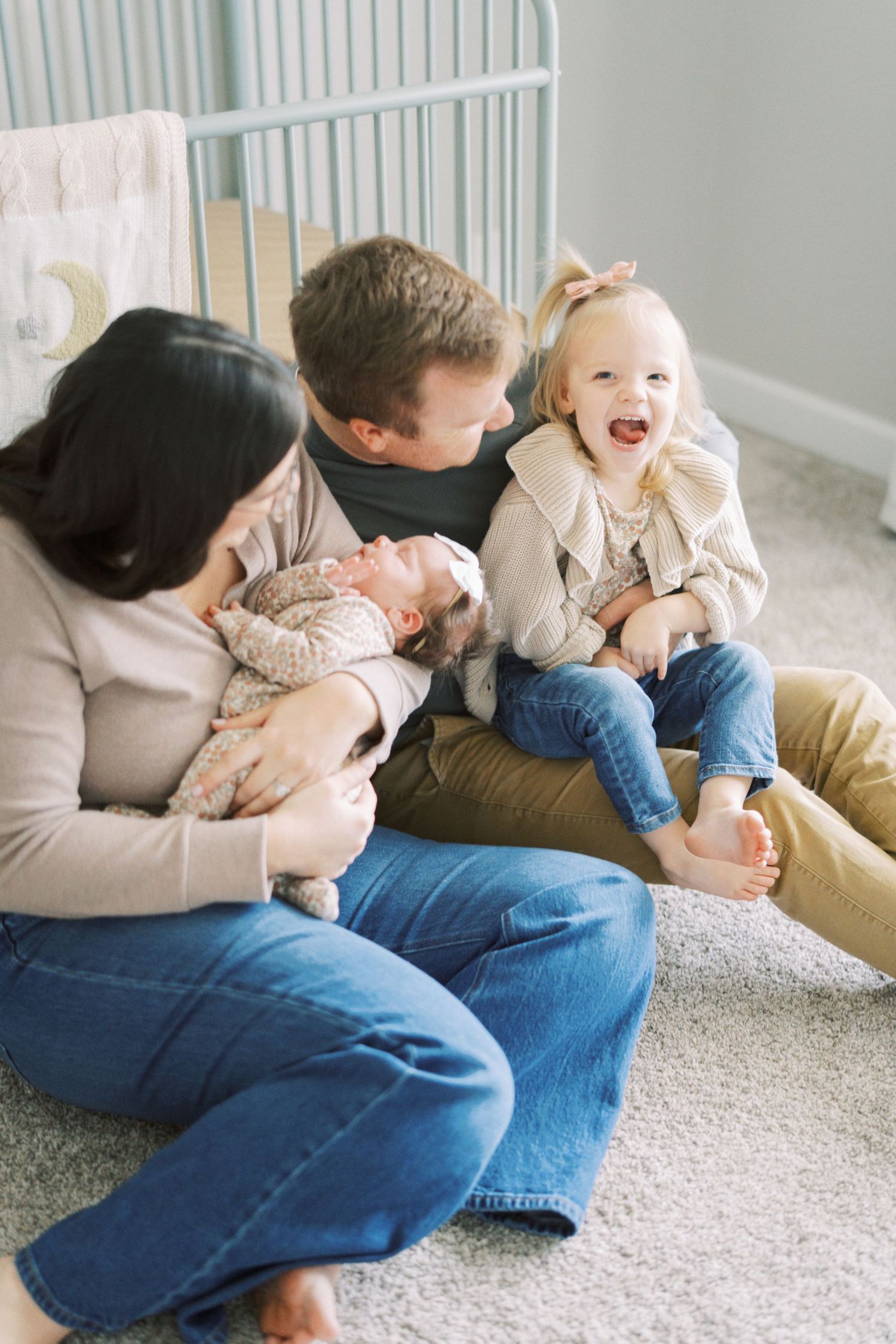 Family lounging together on floor with baby and toddler sharing joyful moment at home.