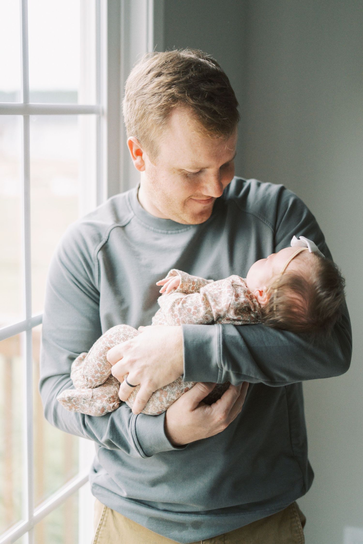 Series of lifestyle shots showing parent cradling an infant near a bright window.