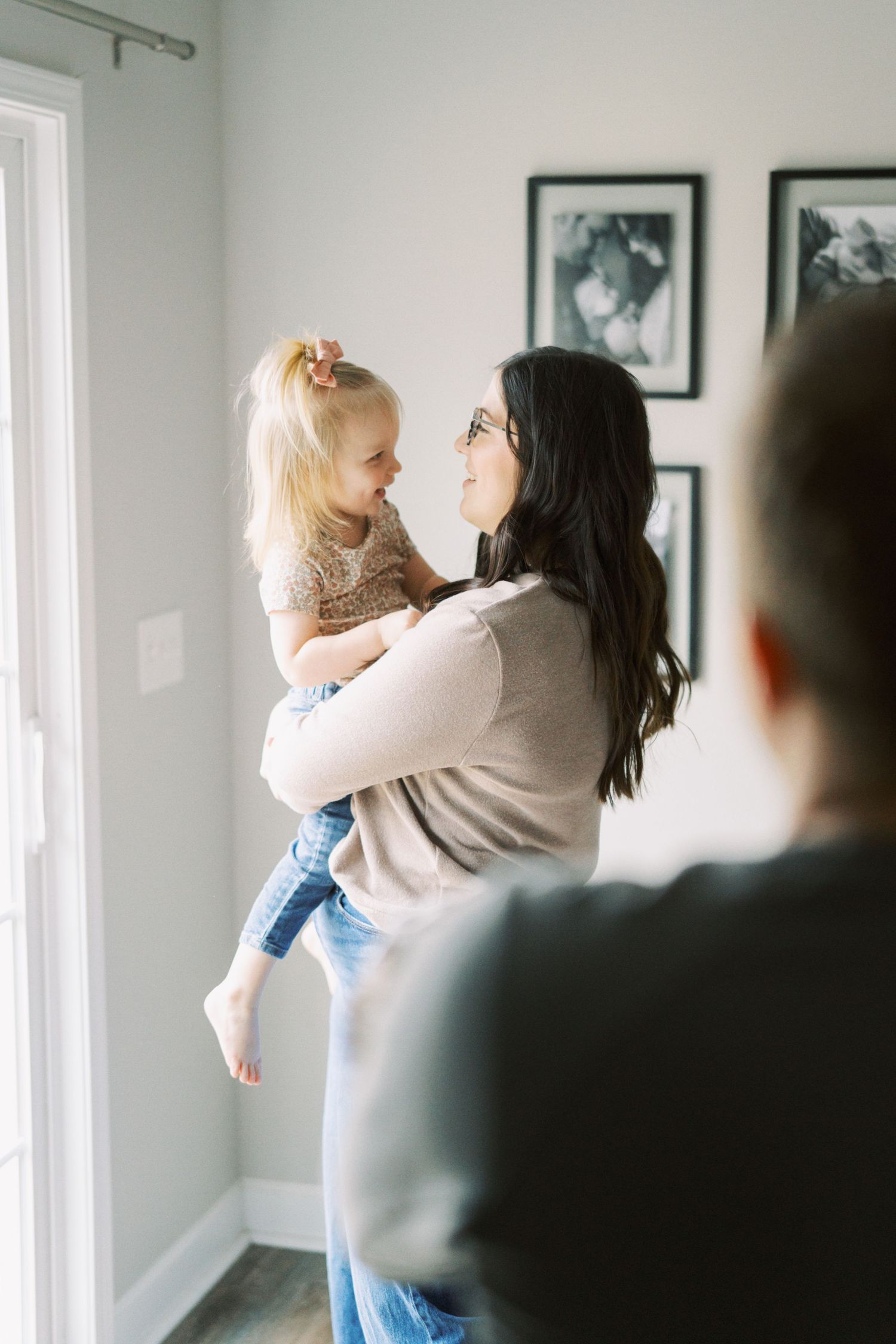 Tender family moment captured in home with natural light streaming through window.