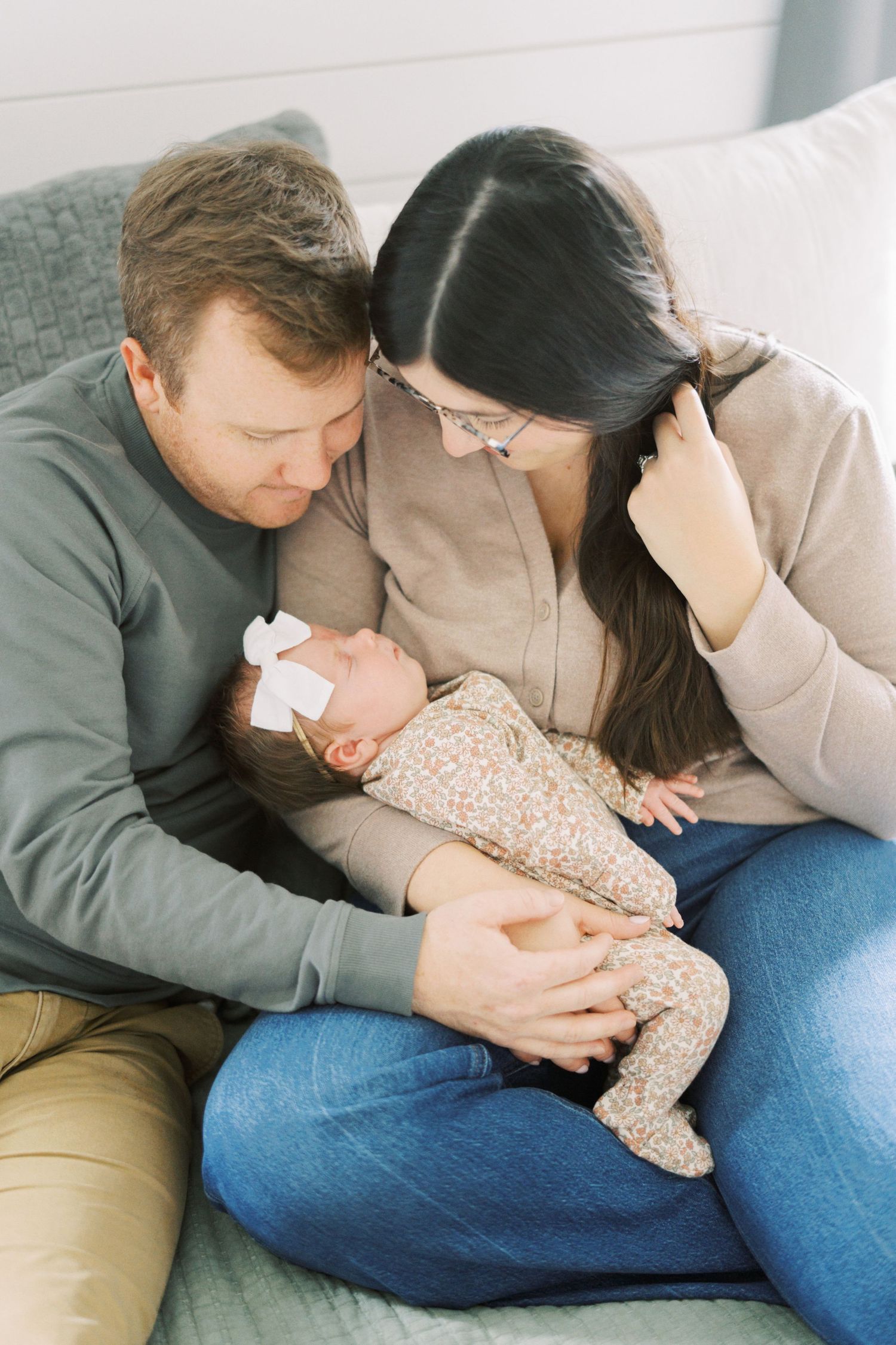 Intimate family lifestyle photos showing parents snuggling with their baby on a light-filled floor.