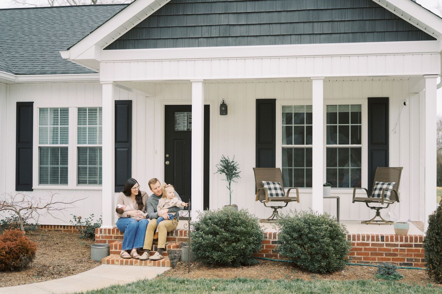 Exterior view of a modern farmhouse style home with white siding and black shutters.