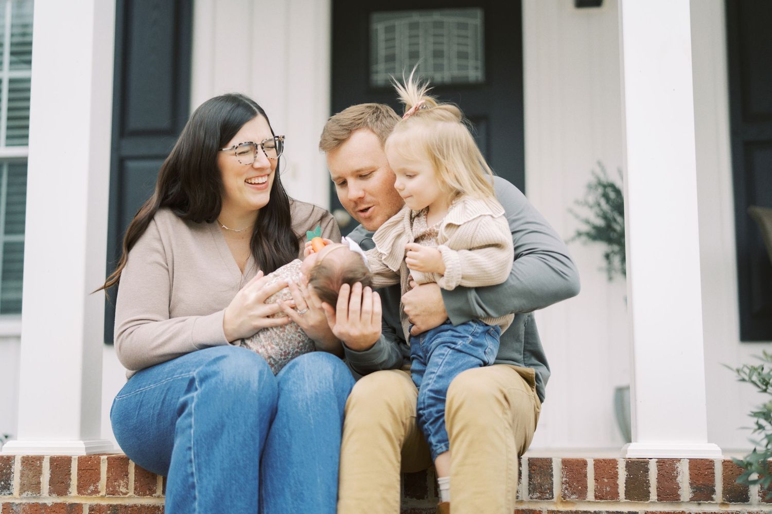 Three people sit together on outdoor brick steps while looking down at something they're holding.
