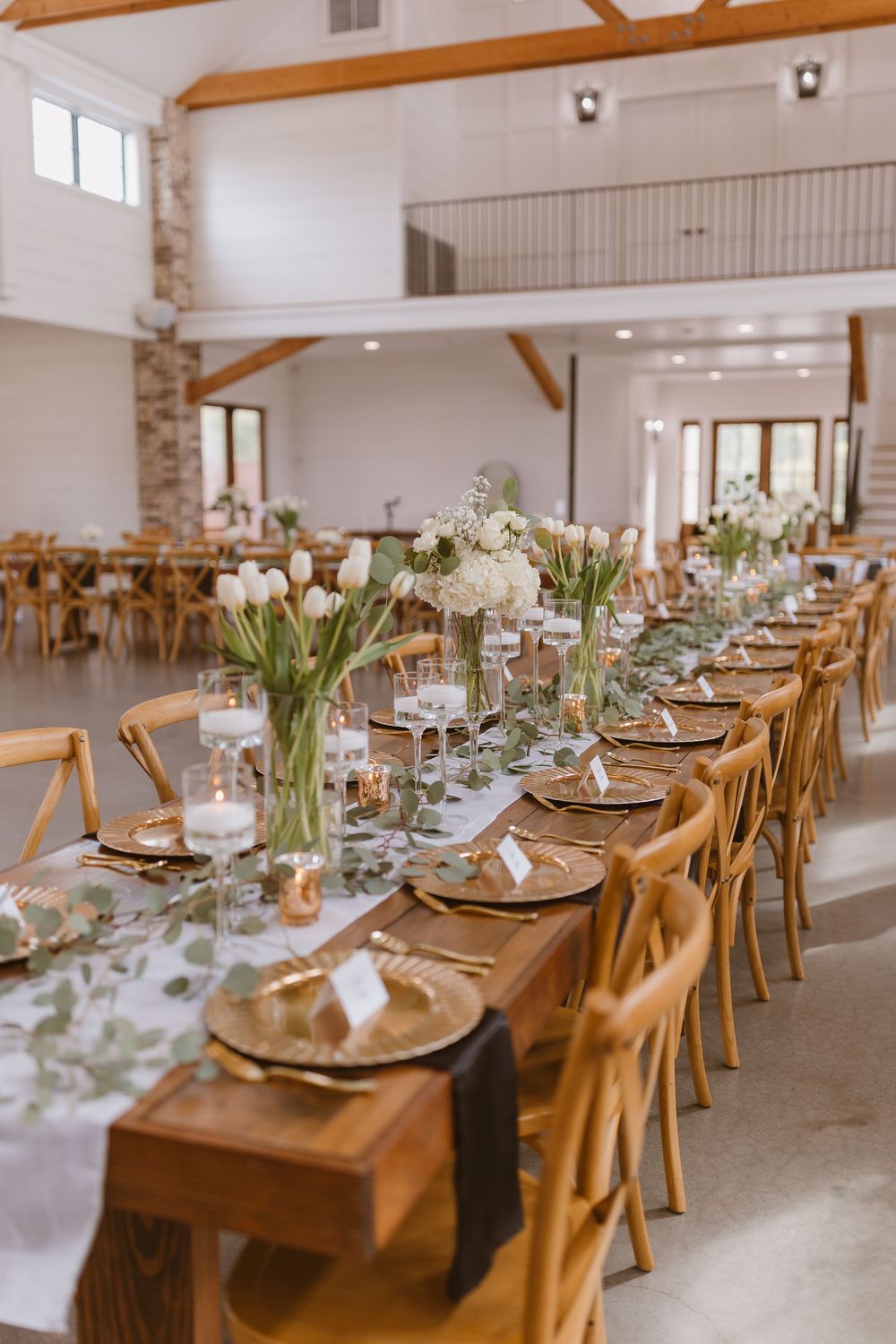 Elegant wedding reception table setting with white flowers and place settings in a modern rustic venue.
