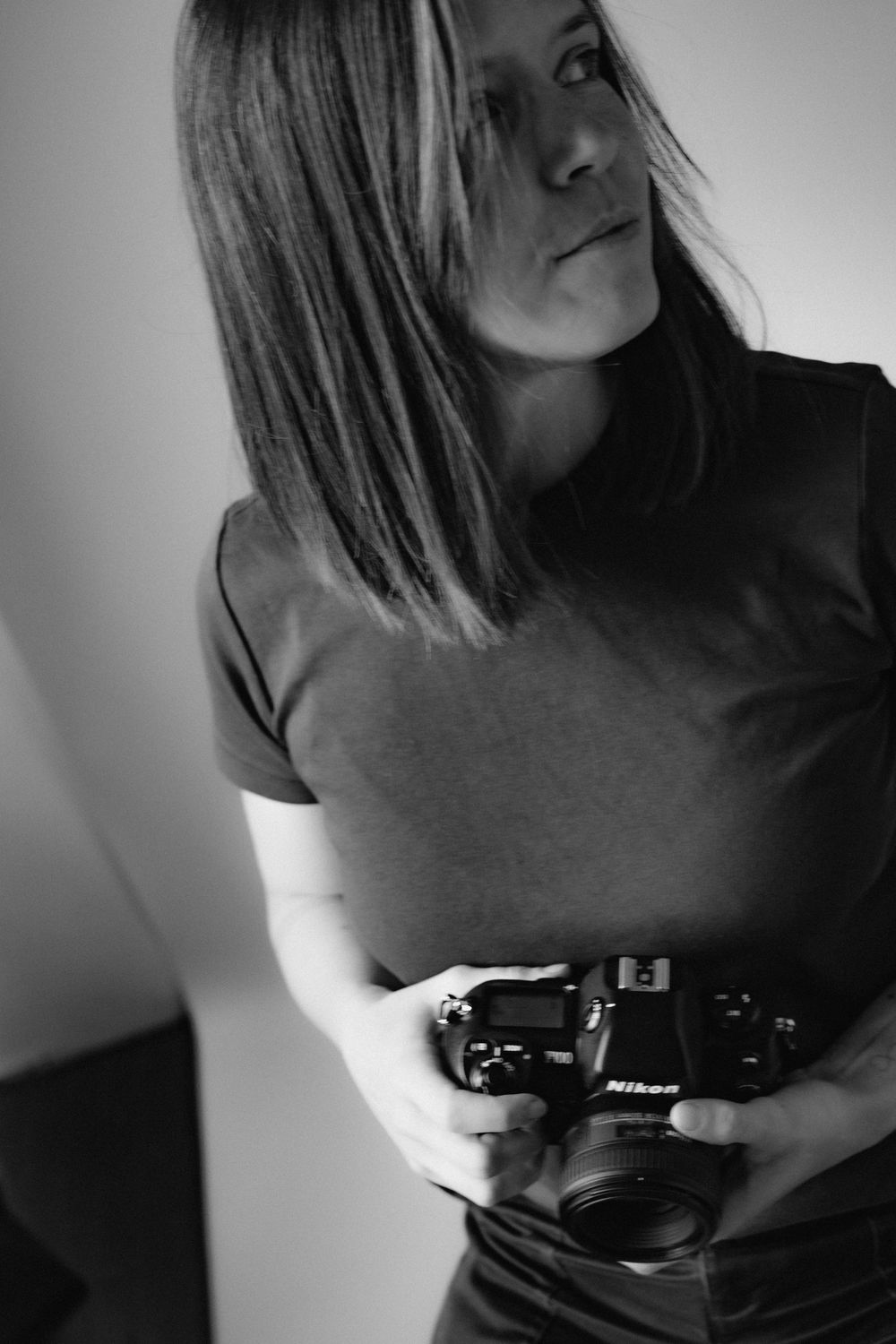Artistic black and white portrait sequence showing someone holding a vintage camera in different angles.