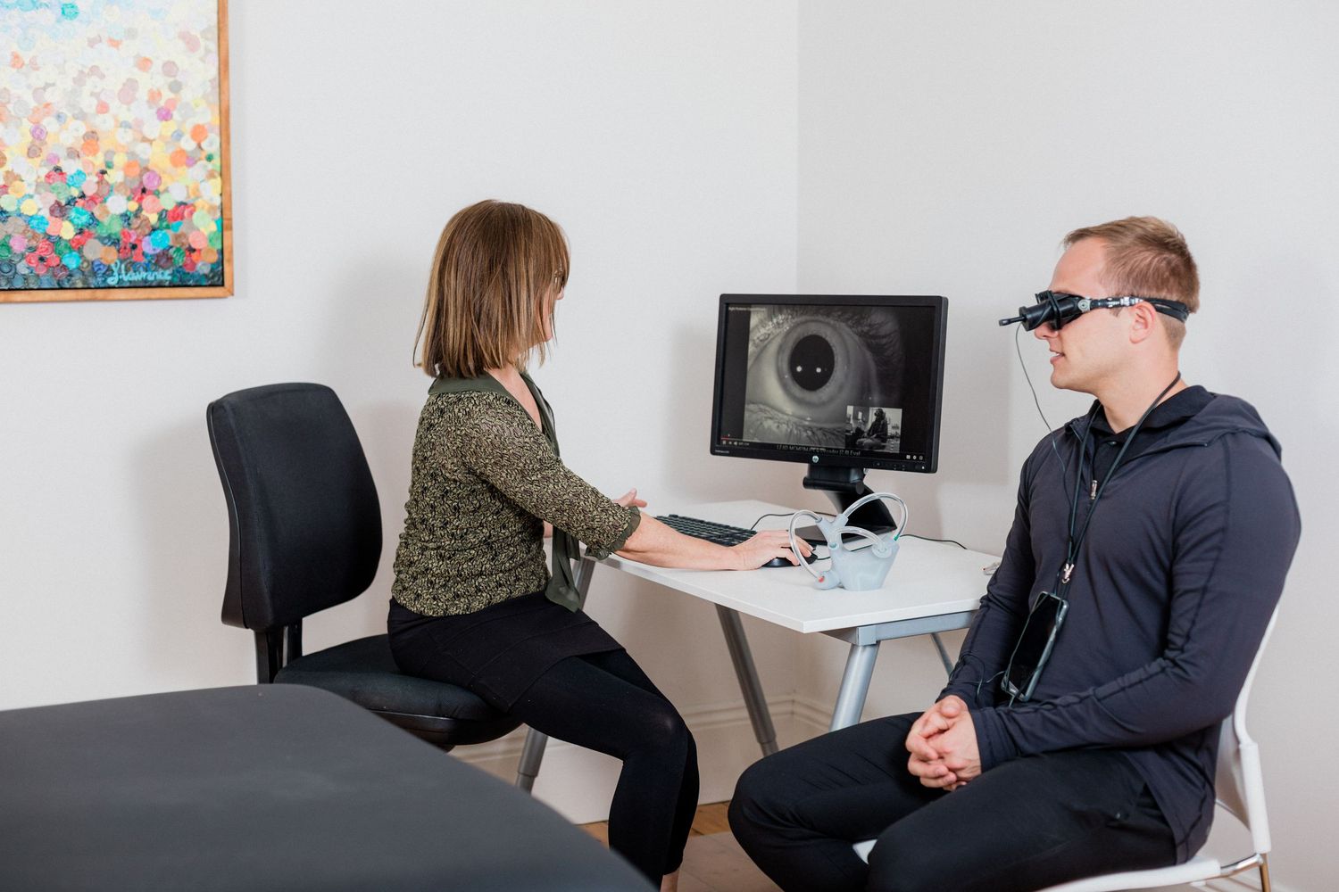 Healthcare provider conducting vision test with diagnostic equipment in medical office.