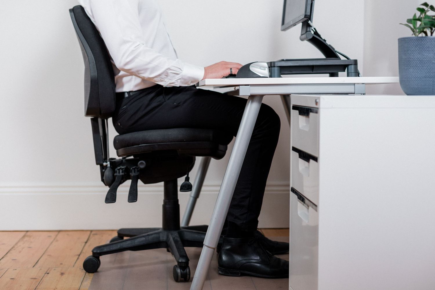 Professional sitting at ergonomic desk workstation in modern office setting.