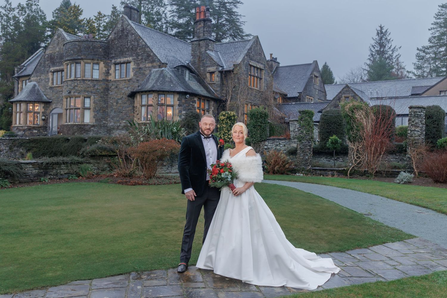 A grand stone lodge with Tudor-style architecture sits nestled among evergreen trees.