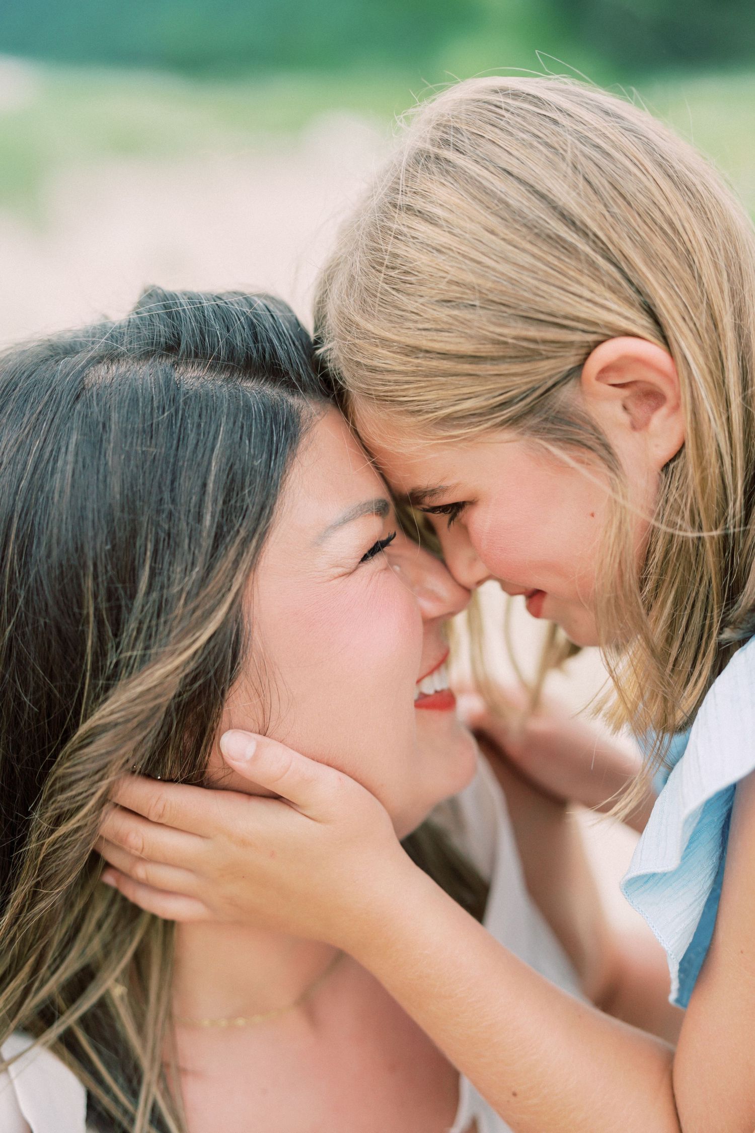 Two figures share an intimate close-up moment with their faces together while bathed in soft natural light.