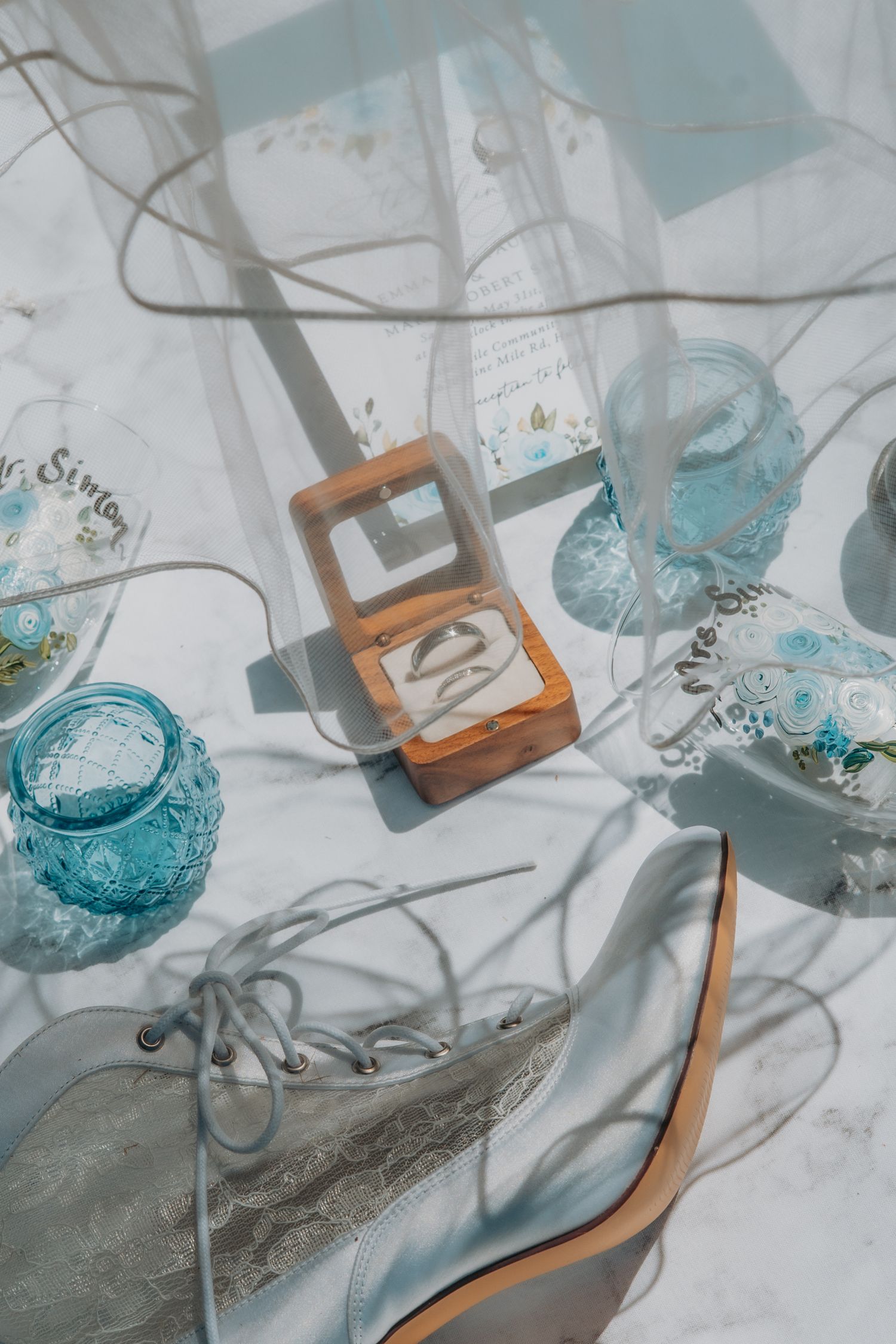 Multiple shots of a vintage teal glass bottle and wooden box arranged artistically on white fabric with soft shadows.