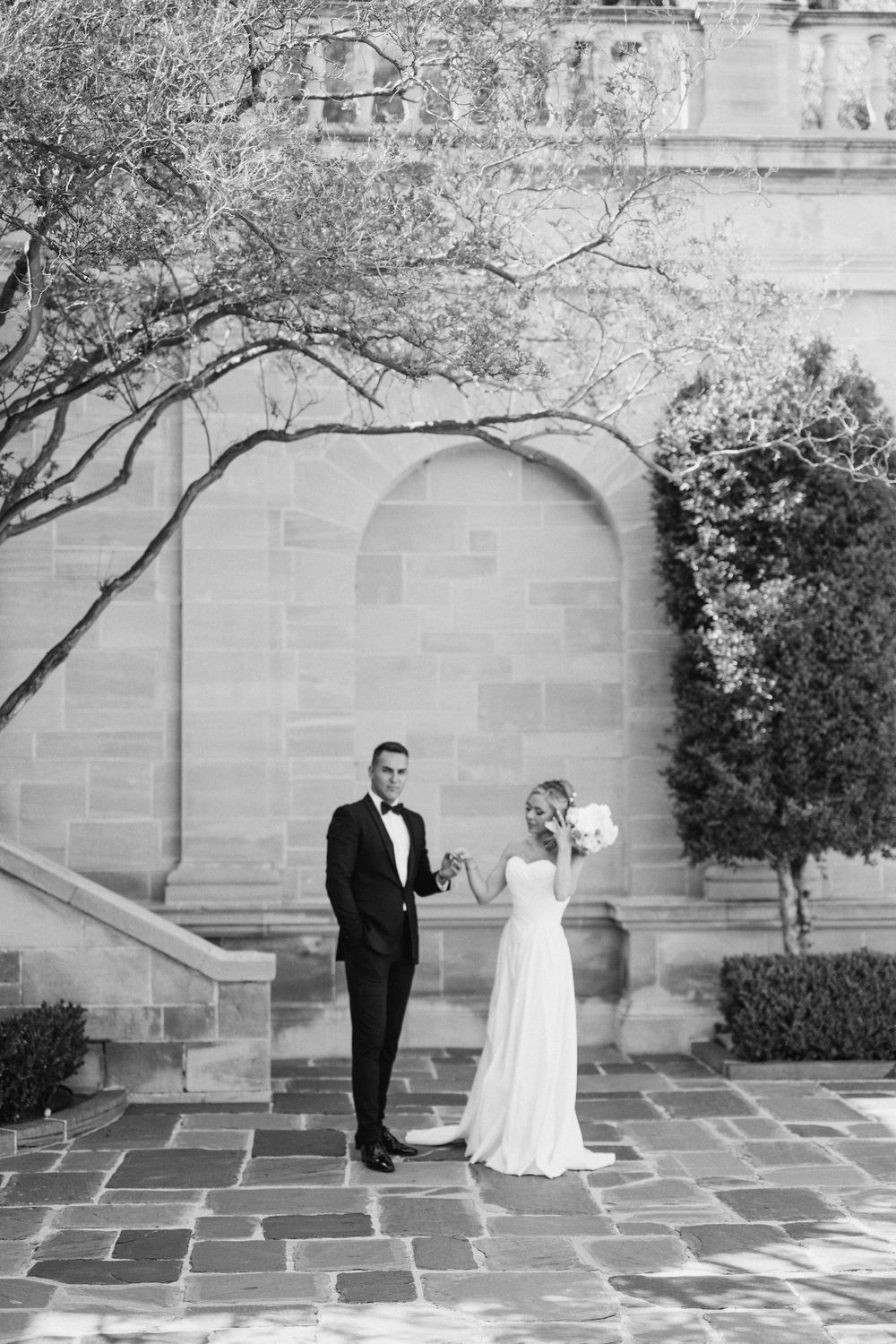 A series of black and white photos showing a couple's first look moment at their wedding by a stone wall.