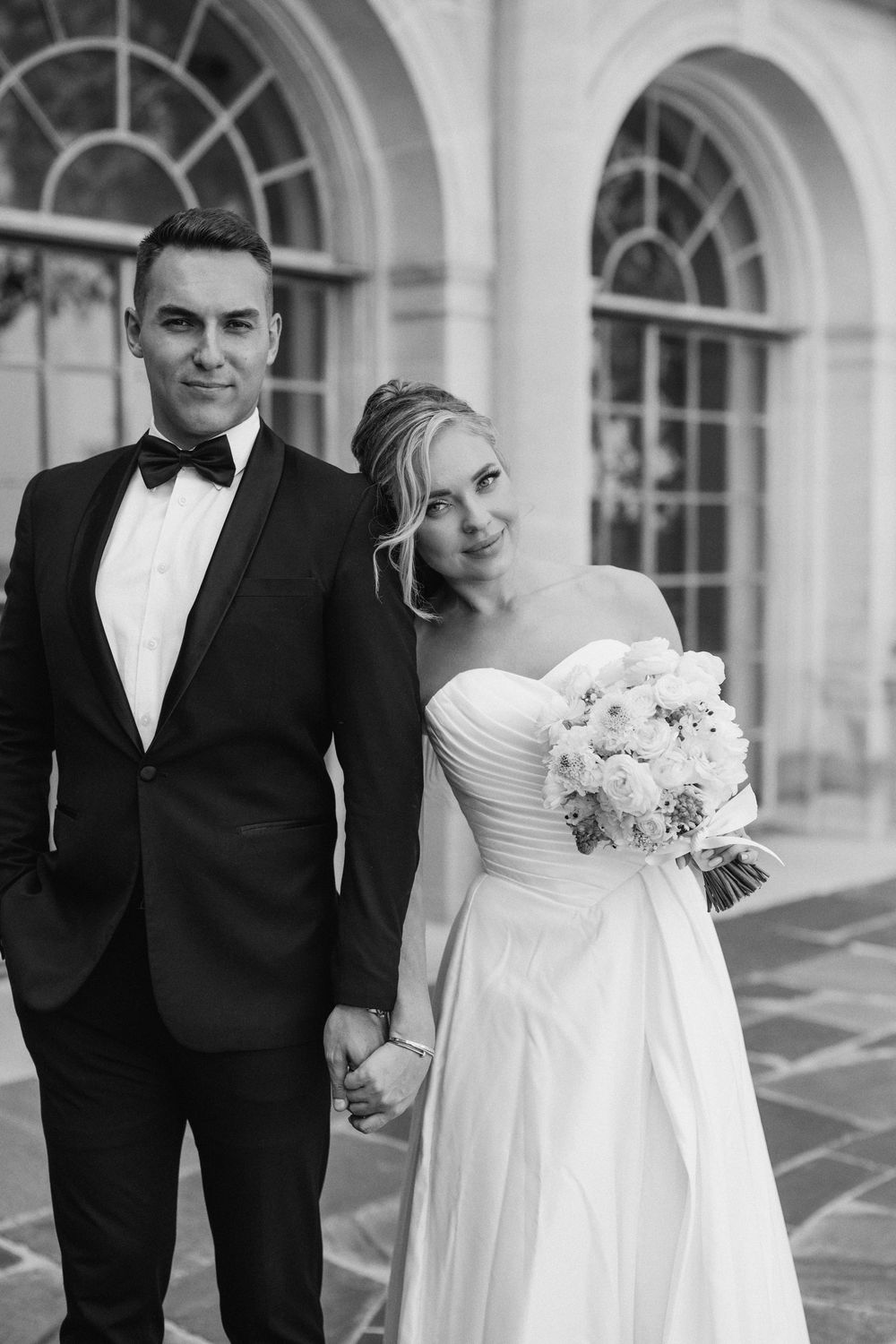 Black and white wedding portraits captured beneath elegant arched windows.