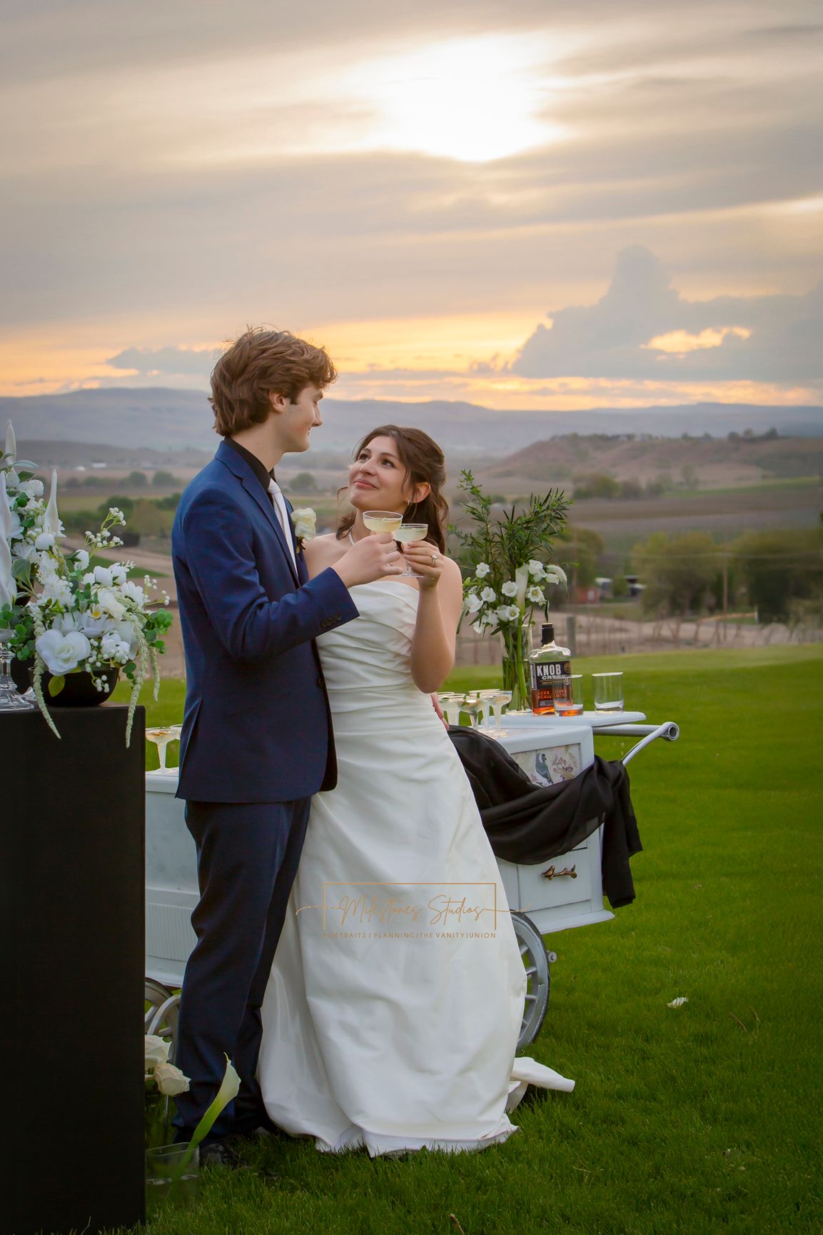 sunsetting behind bride and groom holding champagne