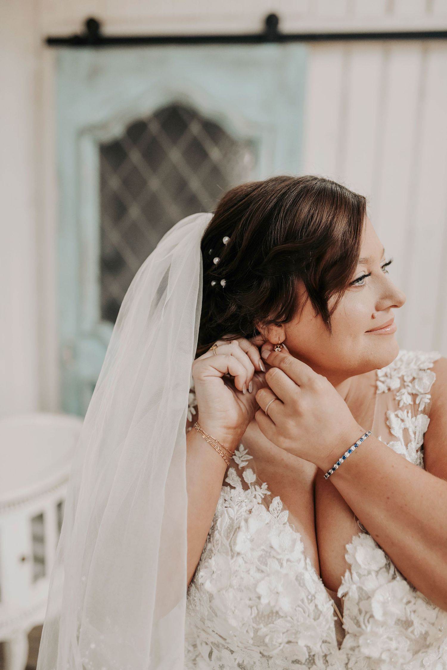Bride smiling while putting on her delicate earrings before the ceremony